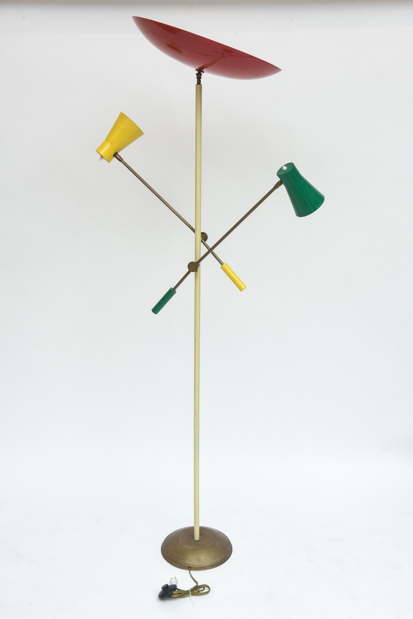 1950s Italian floor lamp with two adjustable brass arms and enamel painted shades that swivel to aim light where needed. The disc-shaped reflector at the top measures 19