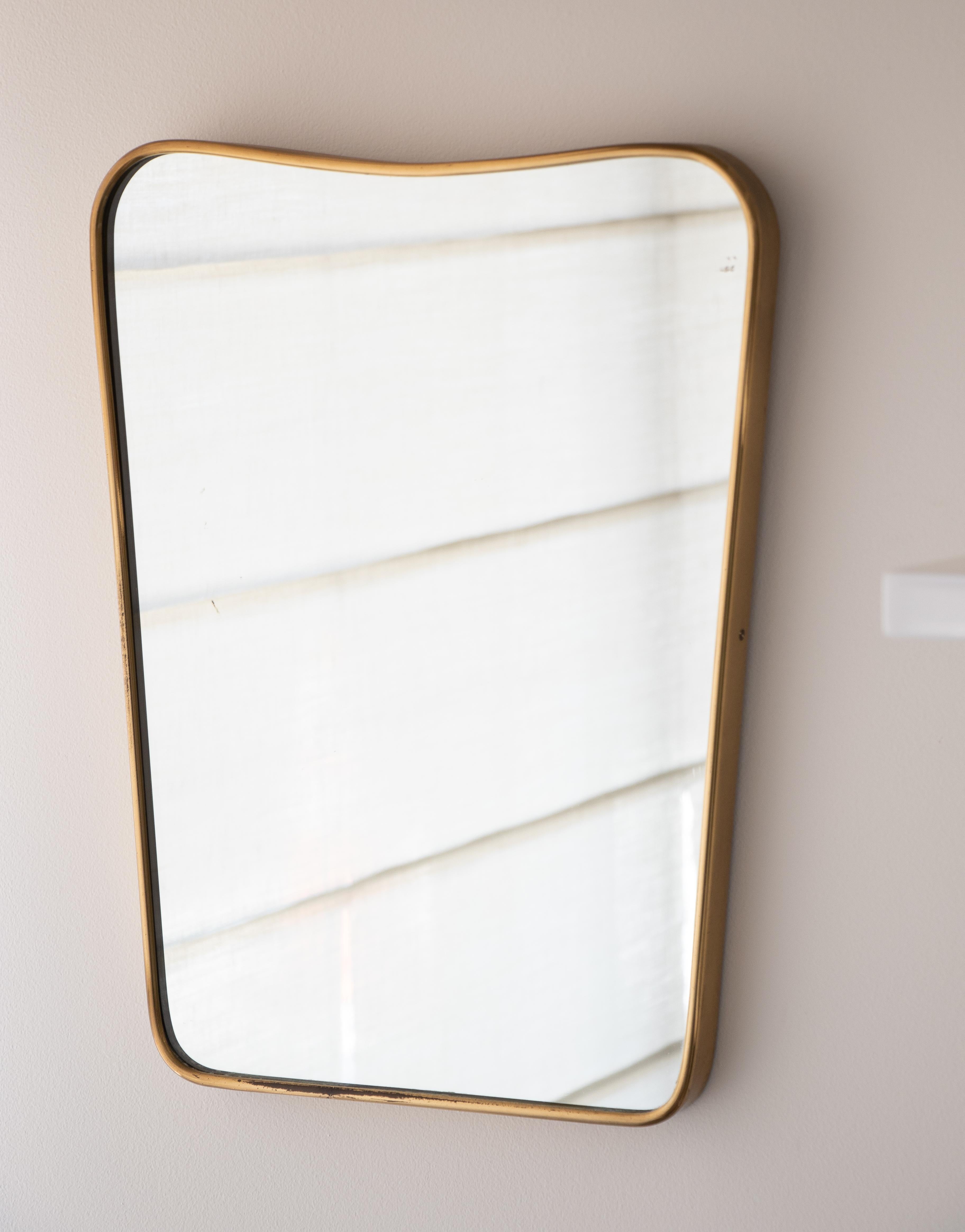 Vintage Italian brass mirror from the 1950s. Wood backing with brass frame around mirror. Wavy top detail in the style of Gio Ponti. Nice age and patina to brass. Measures: Top width 13.5