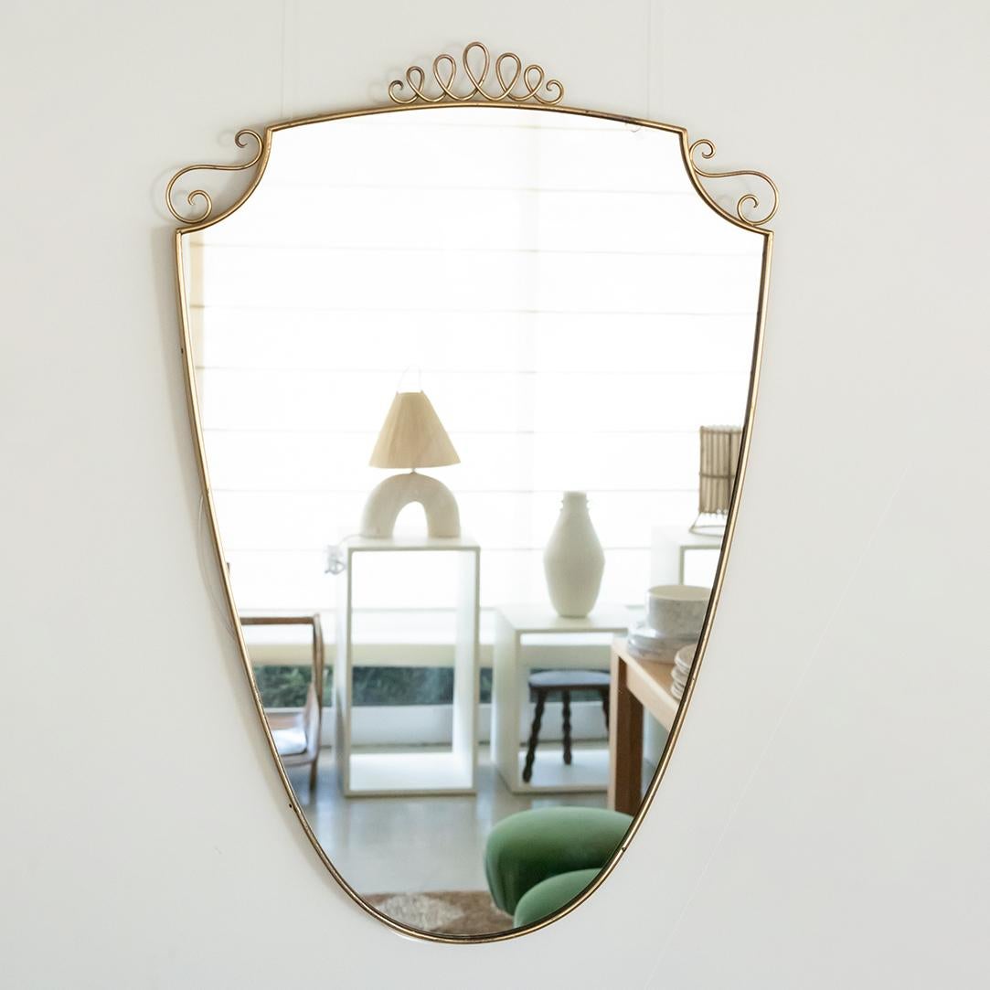 Vintage Italian brass mirror in the shape of a shield with brass loop detail on top. Original brass finish with nice age and patina. Original mirror has one small chip under mirror near top. See photos.