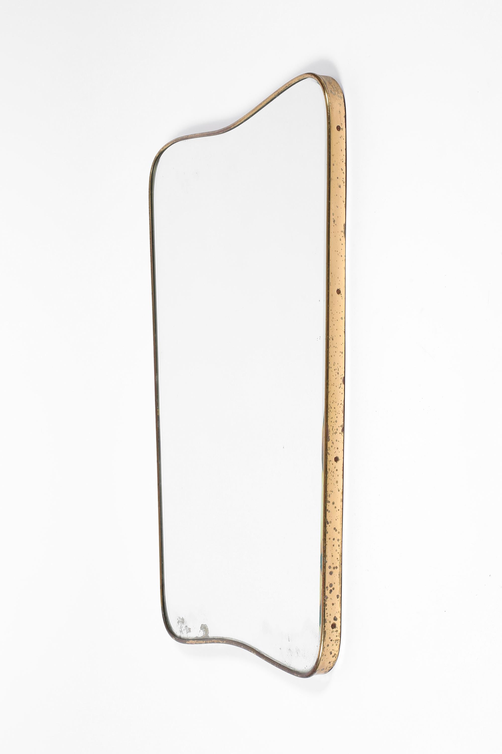 Miroir encadré en laiton patiné, de forme bouclier, avec plaque d'origine biseautée et légèrement roussie, à la manière de Gio Ponti. A.I.C., c. 1950.