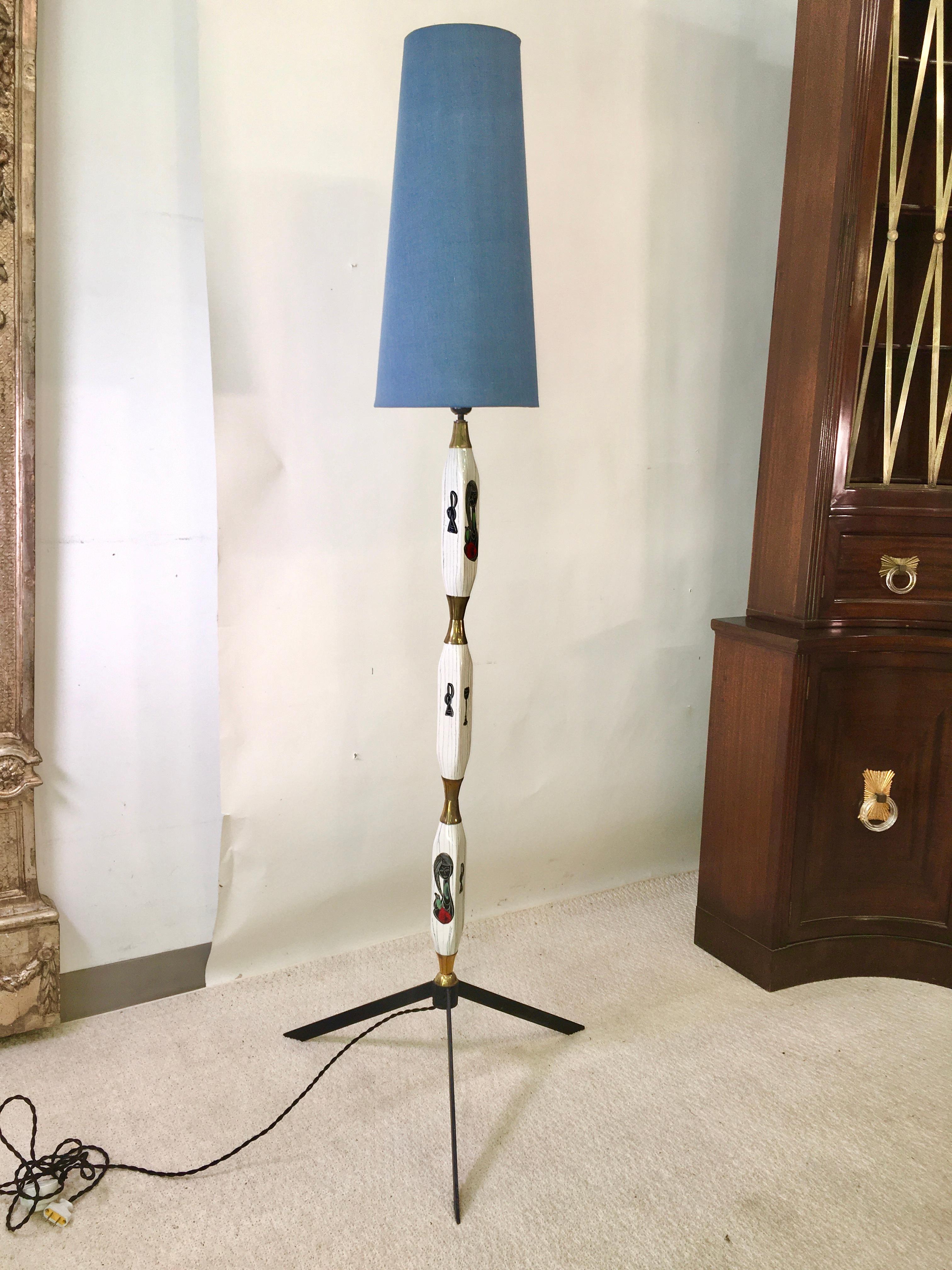 1950's Italian floor lamp adorned with several glazed ceramic vessels in highly stylized asymmetric form. separated by diabolo form hourglass brass spacers and standing on a black metal tripod base . Hand-painted abstract figures and objects on each