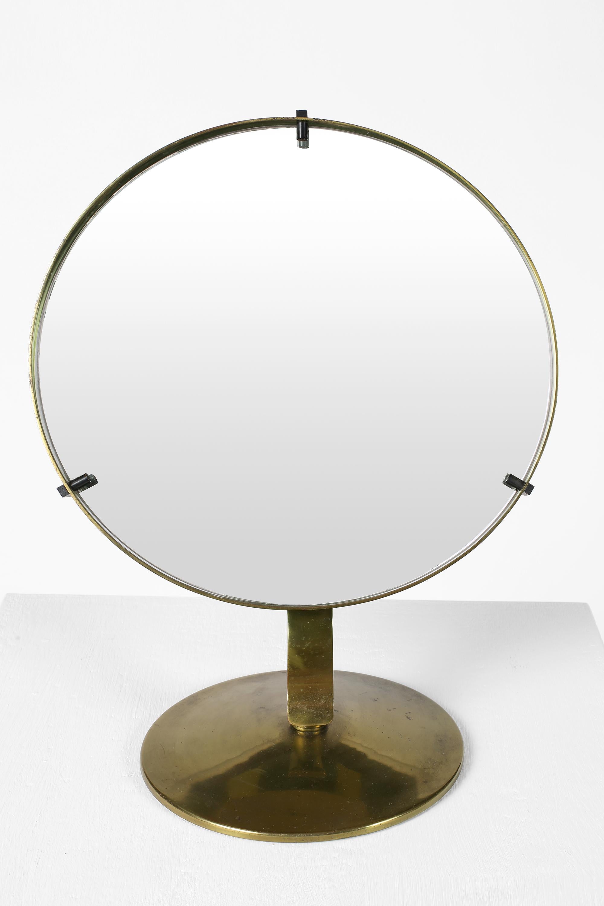 A mid-20th century circular brass vanity mirror with adjustable ball-joint base and original plate. Italian, c. 1950s.