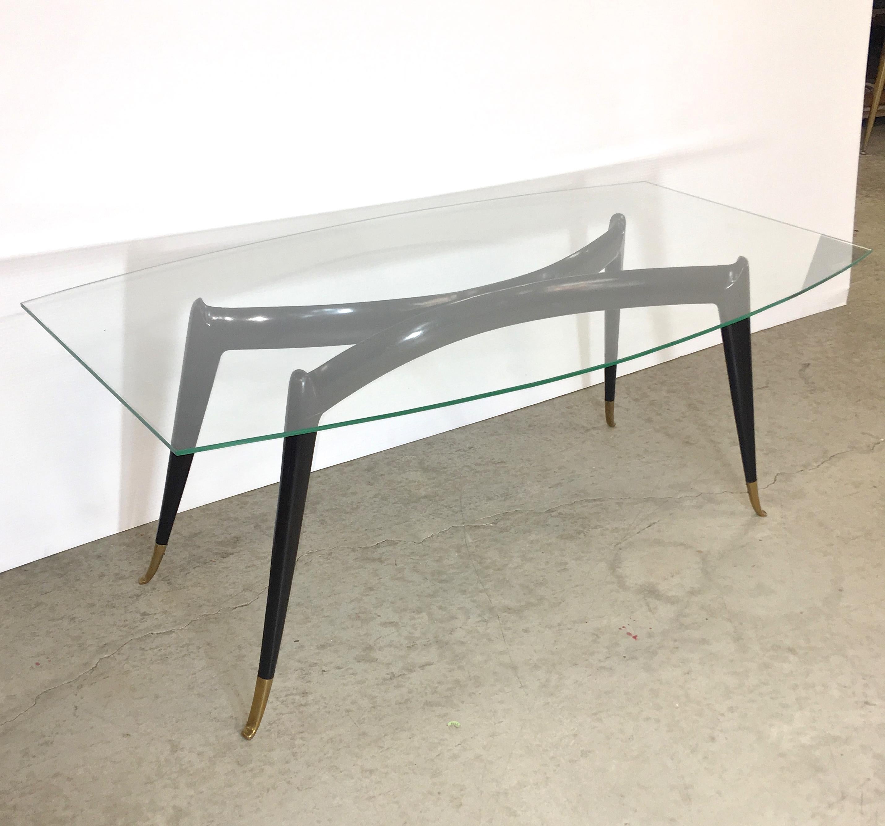 1950's Italian coffee table attributed to Guglielmo Ulrich. 
Ebonized mahogany and solid brass sabots, 
Boat shaped glass top 46 inches by 25 inches.
Table base dimensions without glass 18.5 inches high by 39 wide x 16 deep, toe to toe.
For a