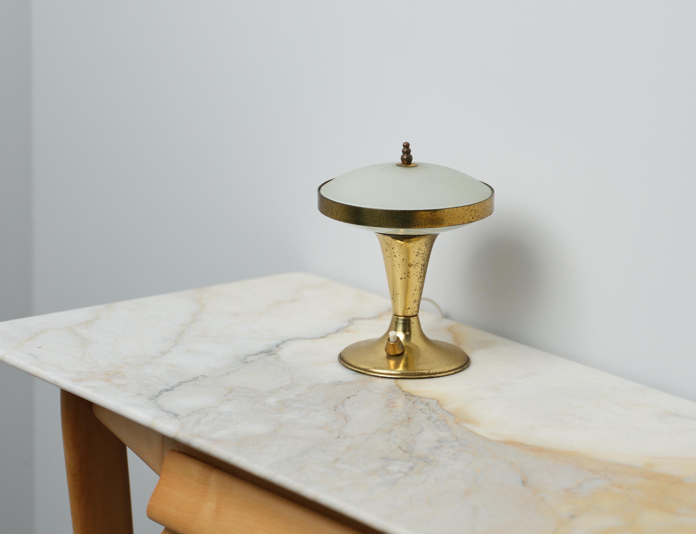  1950s Italian Brass Table Lamp. This lamp embodies the elegance and sophistication of the era, featuring a genuine brass construction with a beautifully aged oxidized patina. Its frosted glass shade adds a touch of vintage charm while diffusing a