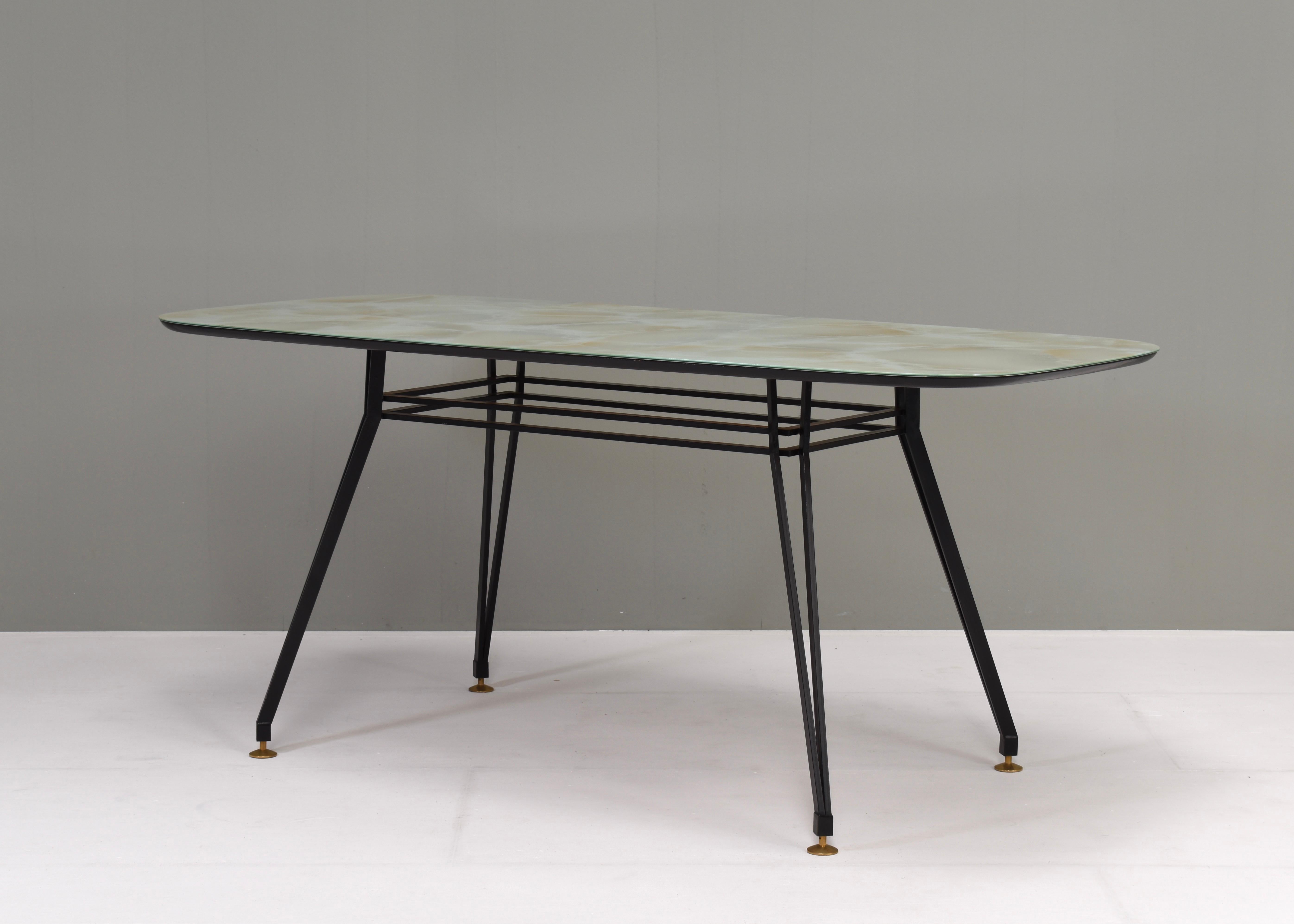 Italian dining table from the 1950’s.
The table has a black lacquered metal base with in height adjustable brass feet. The table top has a wood edge with a glass top and a stone print pattern underneath.

Designer: Unknown
Manufacturer: