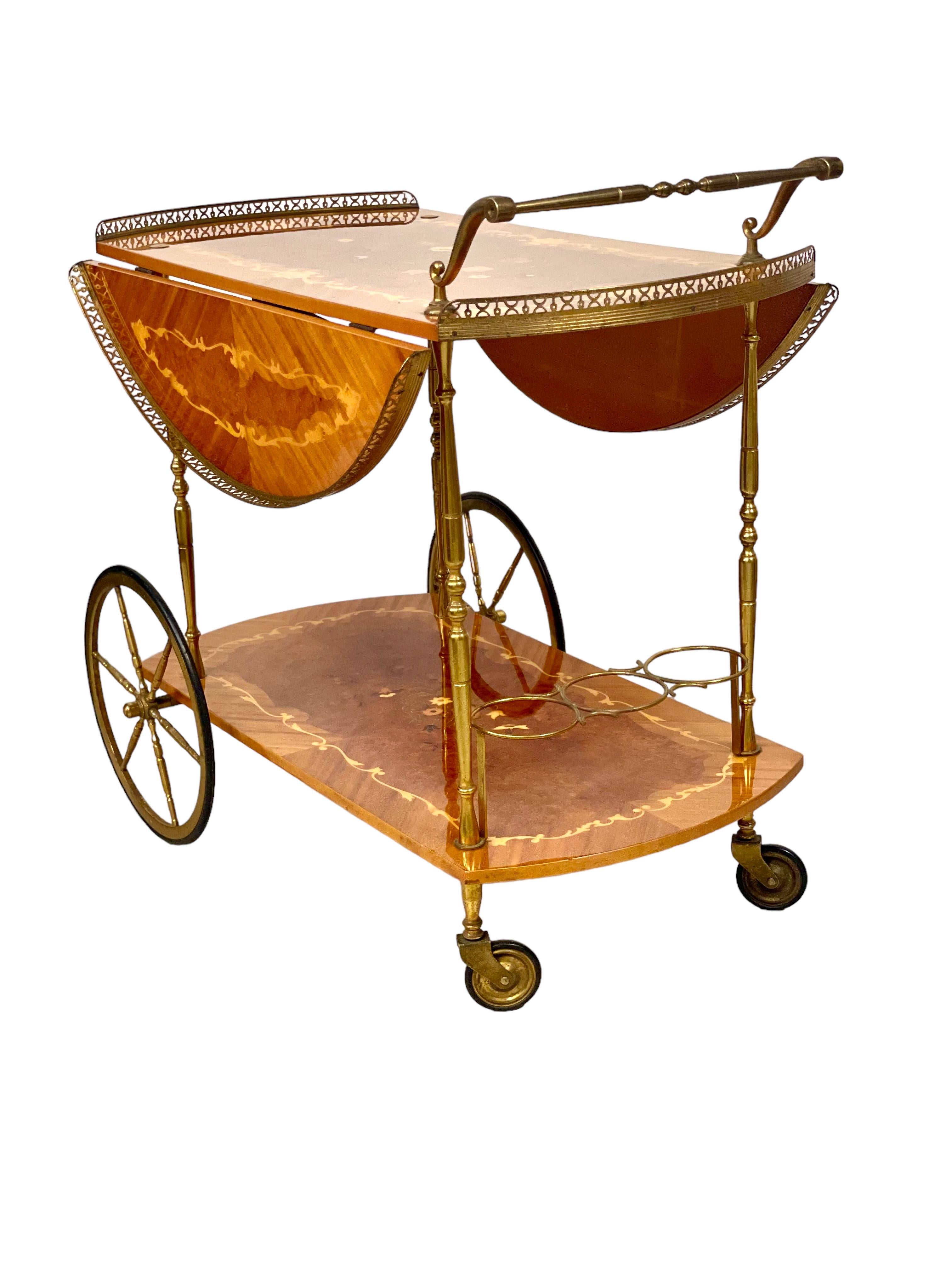 A very stylish mid-century Italian drop-leaf bar cart, or drinks trolley, beautifully decorated with fine quality floral marquetry in a variety of lovely wood. Featuring two tiers, the lower one fitted with three useful bottle holders, the cart is