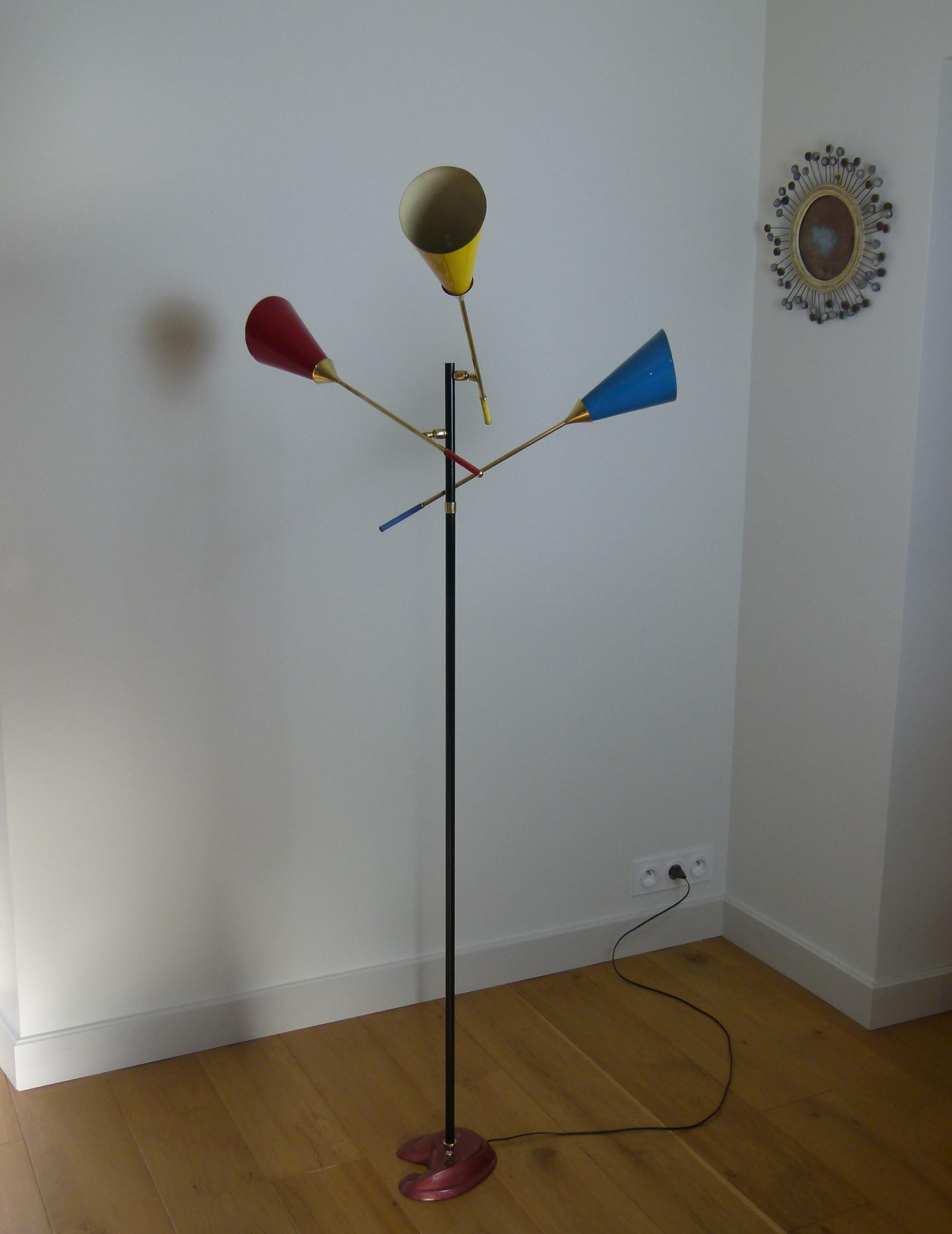 Floor lamp made of metal, brass and cast iron, composed of a colored enamelled cast iron base, representing a painter's palette, on which is fixed a black lacquered metal trunk.
On which are arranged three ball mounted brass arms of light that can