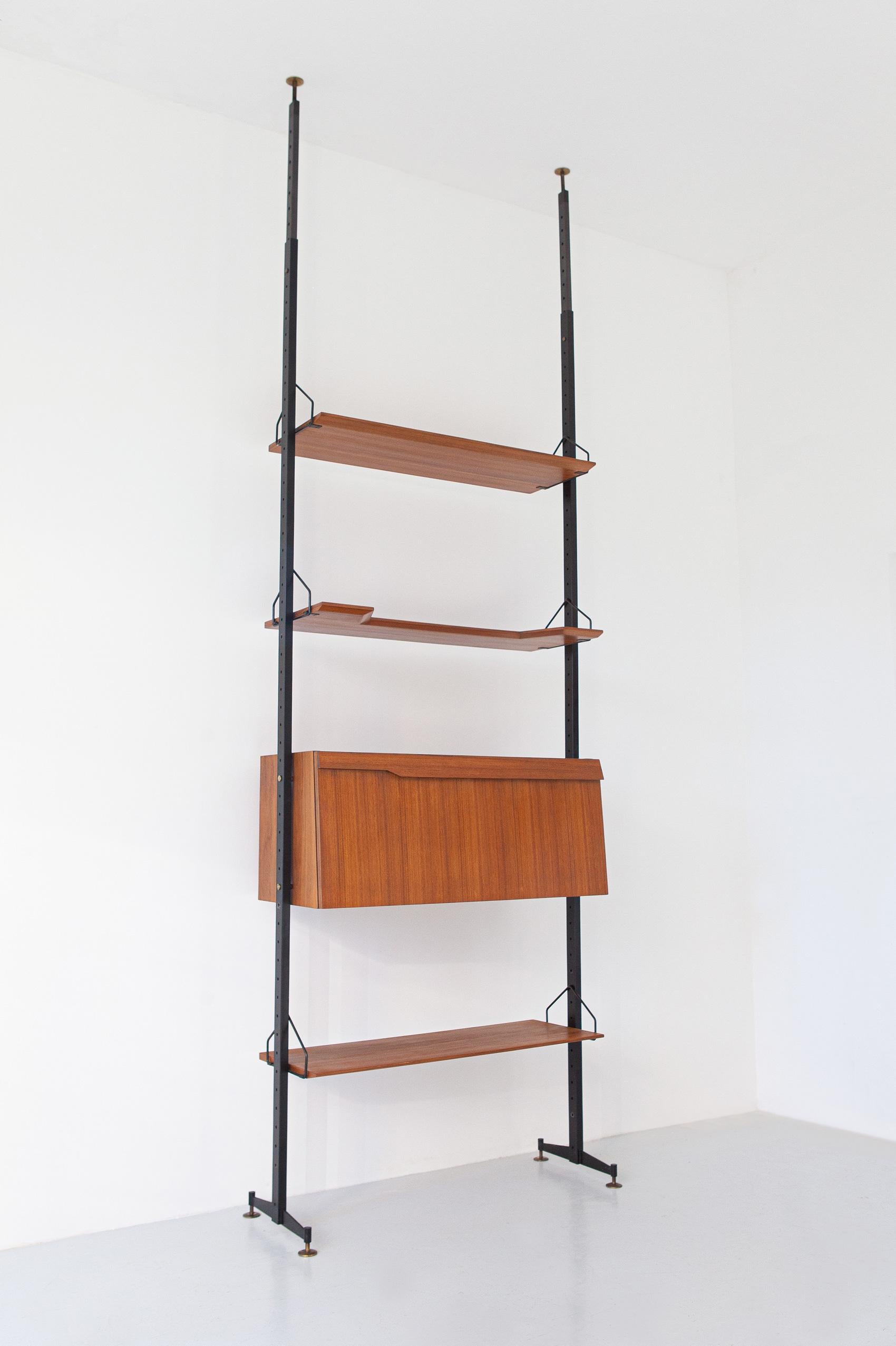 A modern bookshelf system in teak, manufactured in Italy during the 1950s. 

The mounting of this wall unit is with pressure between the floor and the ceiling. 
It is made up of a flap cabinet that can be used also as a small writing desk or a