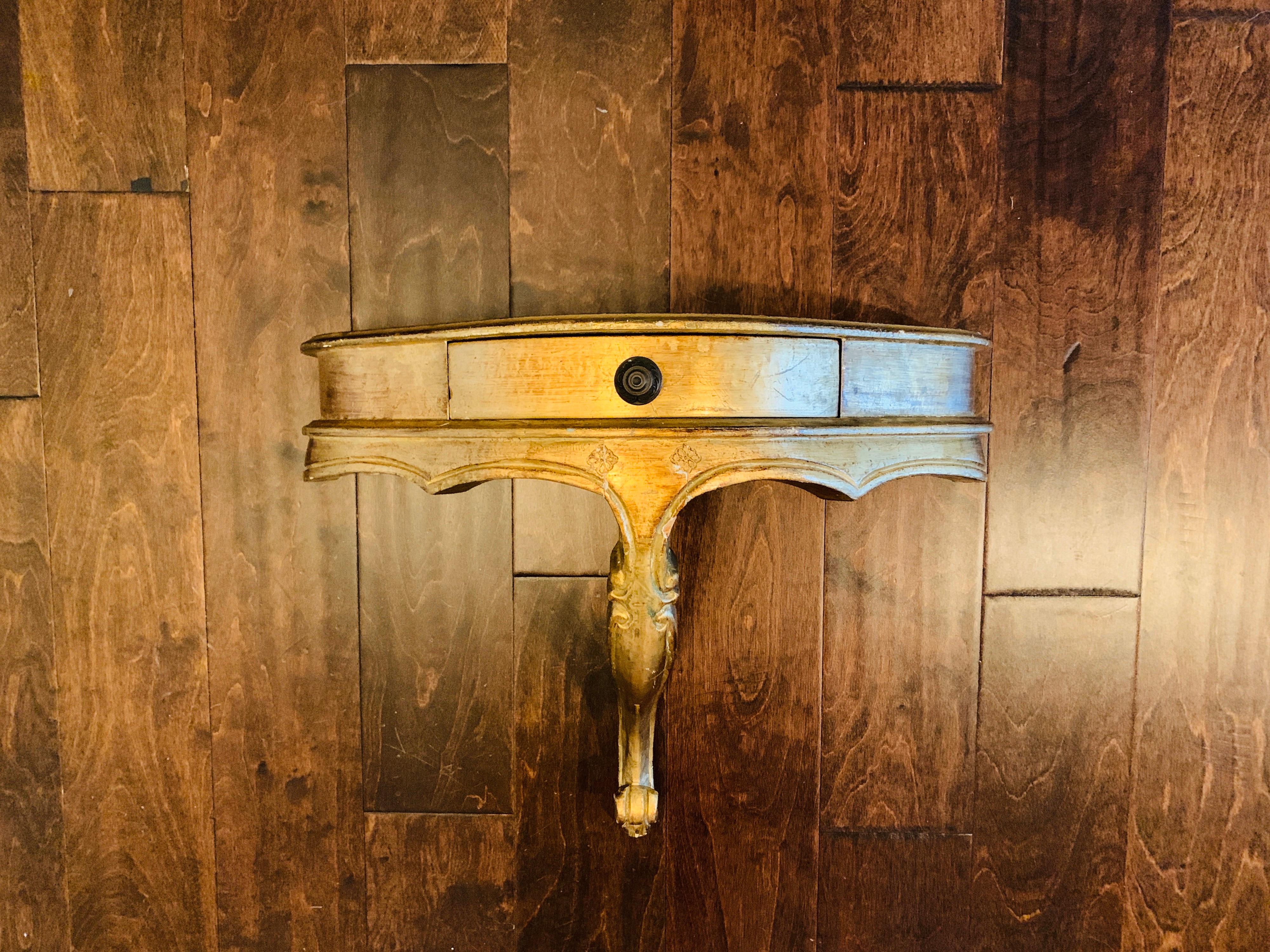 Listed is an absolutely stunning, 1950s Italian Florentine gilt wall hanging demilune shelf. This particular piece is very rare and unusual, as it looks like a standard, smaller Italian wall shelf bracket, though this is an oversized version --