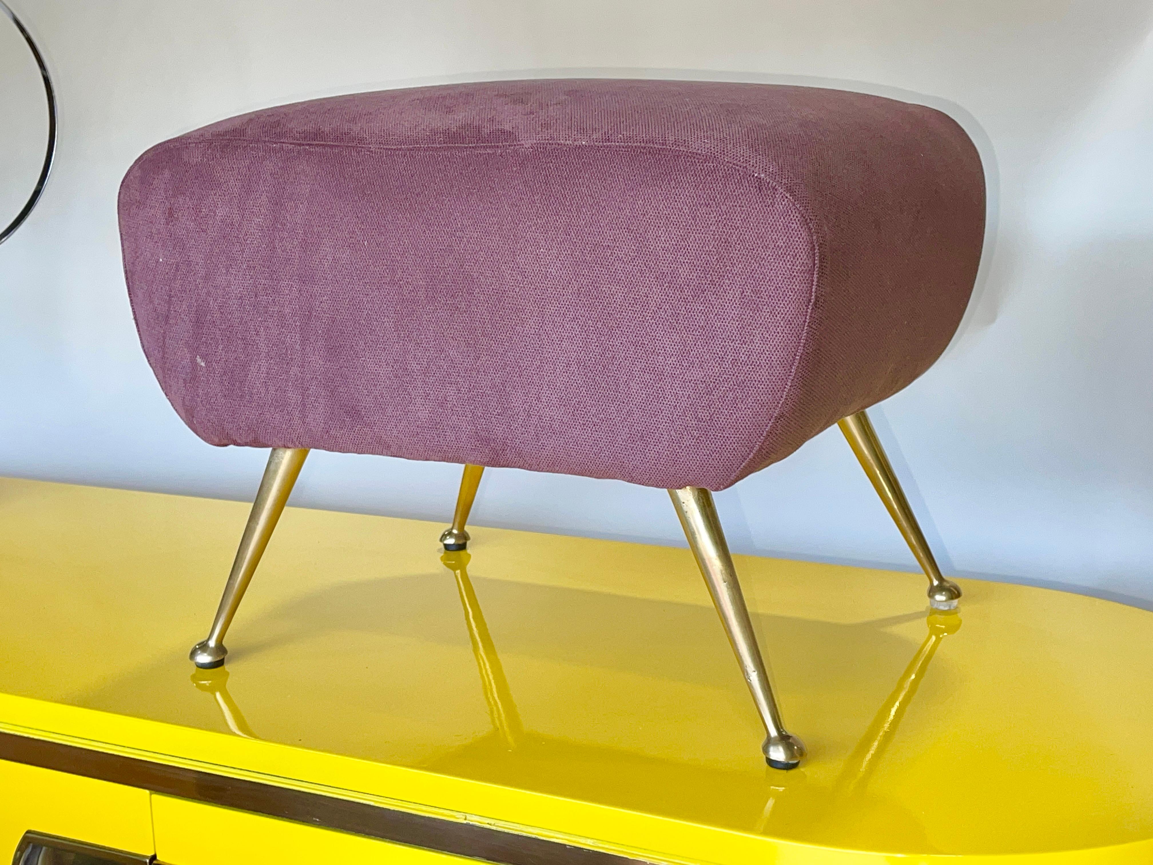 Footstool or ottoman, Italian 1950s, in rectangular slightly kidney bean shape. Wood frame upholstered in dense foam and covered in its original wine colored cotton velvet, standing on four tapered solid brass legs with half-ball feet and rubber