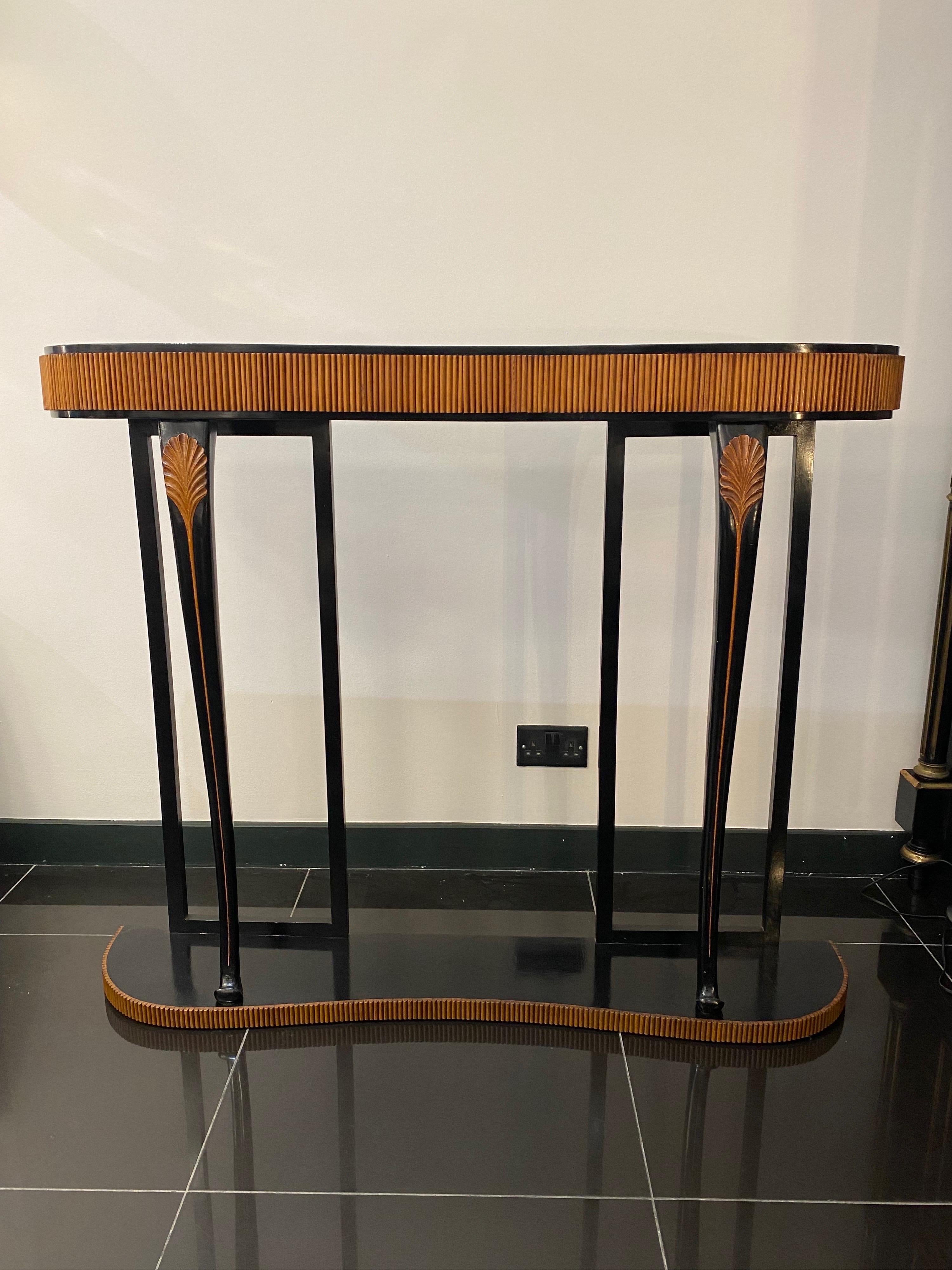 Delightful black lacquer and reeded cherry wood freestanding console table with four secret drawers. The console features two decorative curved legs to the front with carved leaf detailing supported by a kidney shaped stand matching the upper part.