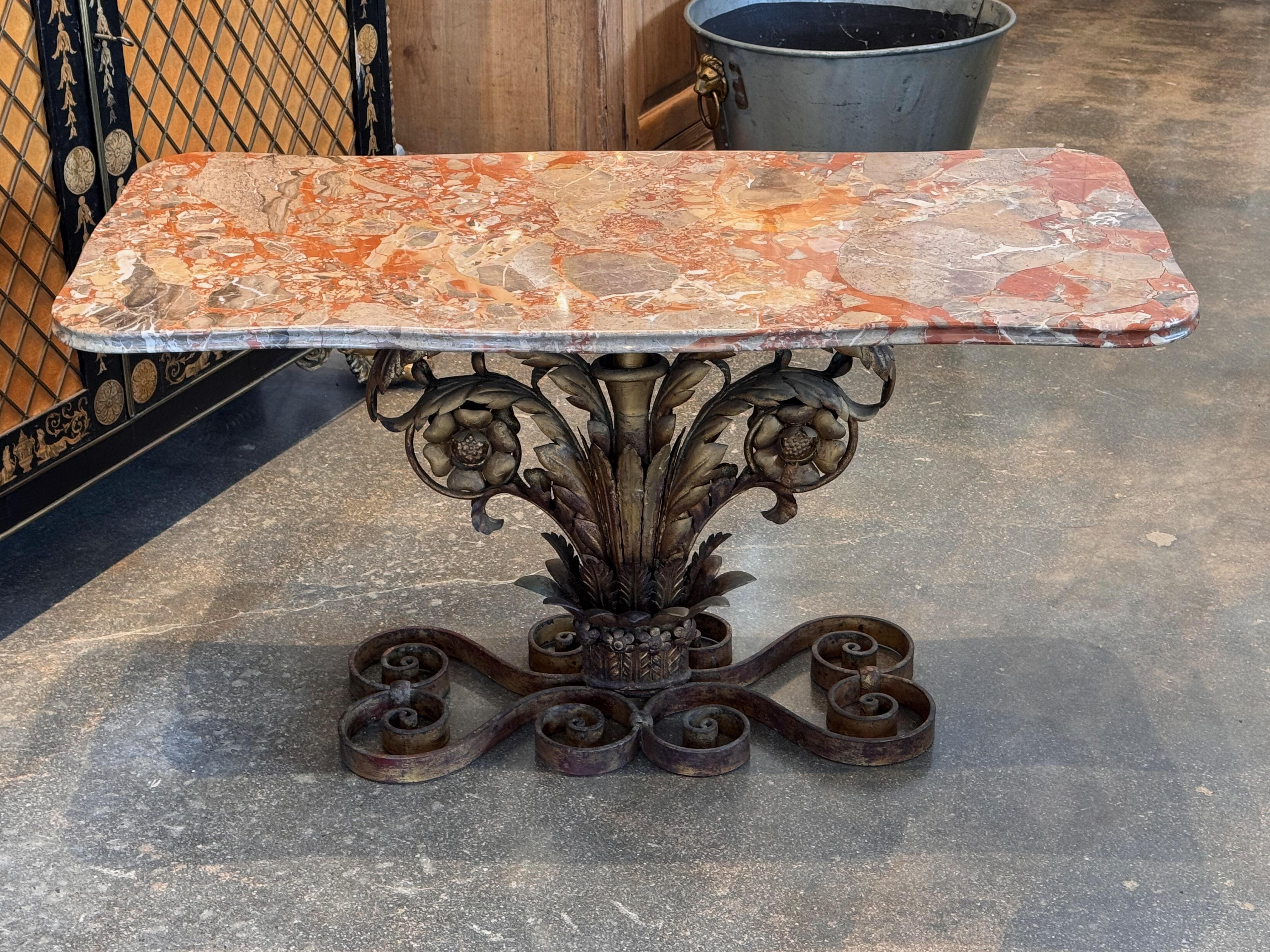 A striking Italian gilt iron console table, featuring an hand-forged base with scrolling acanthus leaves, floral motifs, and intricate detailing. The patinated gilt finish enhances its timeless appeal, embodying the elegance and craftsmanship of