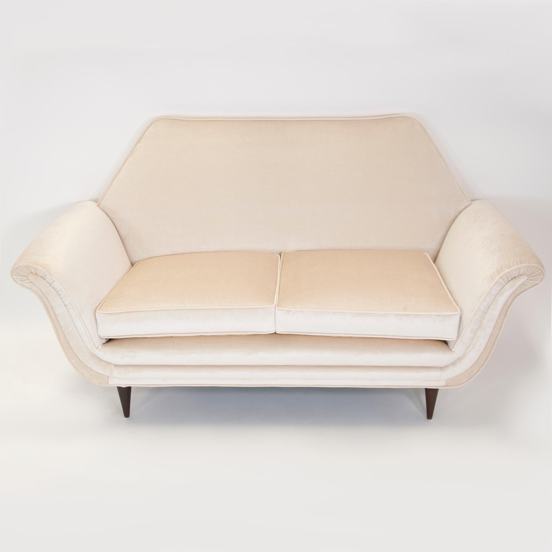 Sculptural Mid-Century Modern Italian love seat in the manner of Guglielmo Ulrich. Restored and reupholstered in an ivory velvet.

Measures: Seat 18 H x 44 W x 20 D
Arm height 23