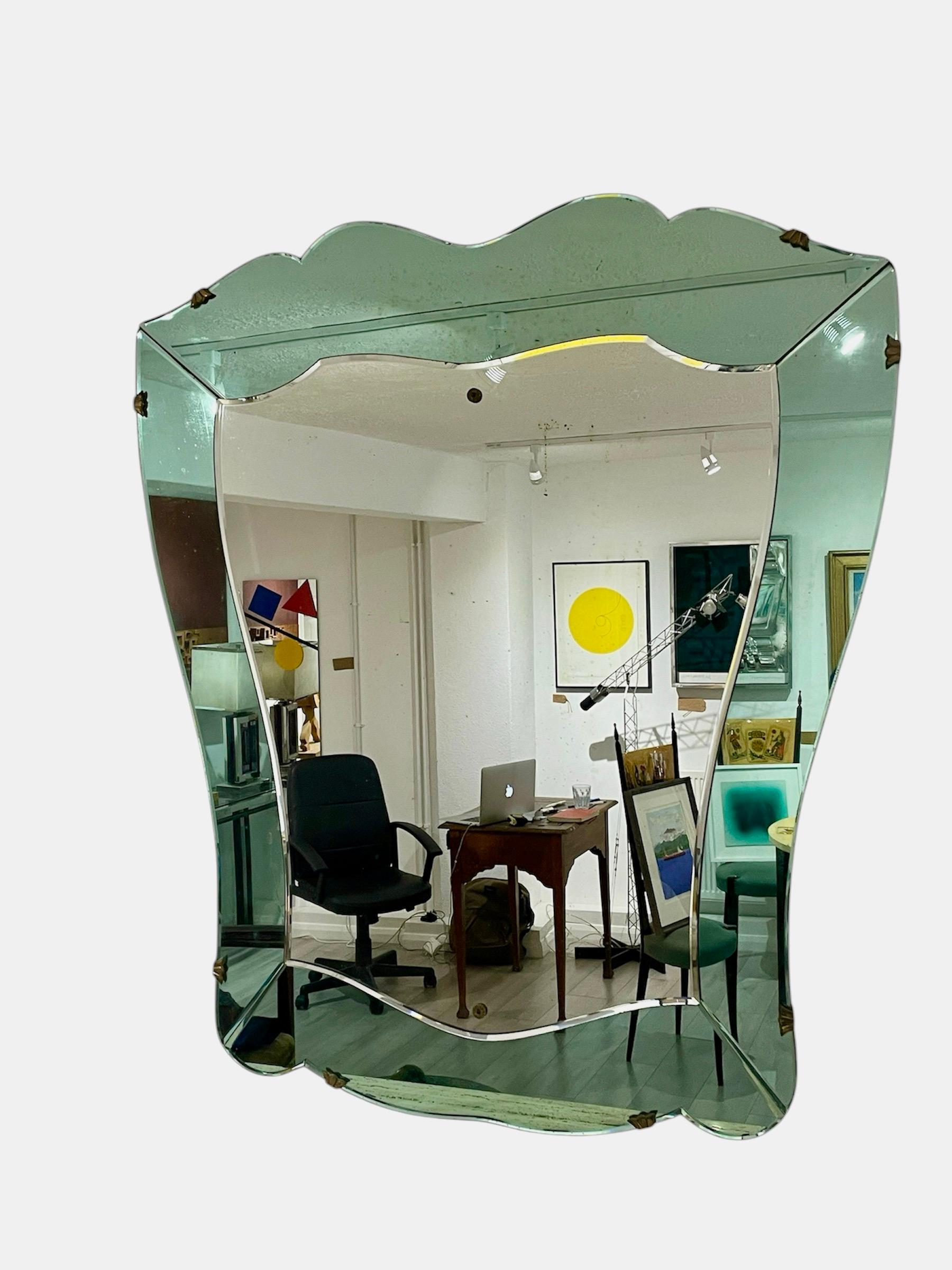 Stunning heraldic shaped Italian 1950s Italian mirror. Beautifully constructed with a solid wood backing and lovely aged brass surround and fixing brackets. Very much in the style of Fontana Arte and made between 1930-1950. A gorgeous statement