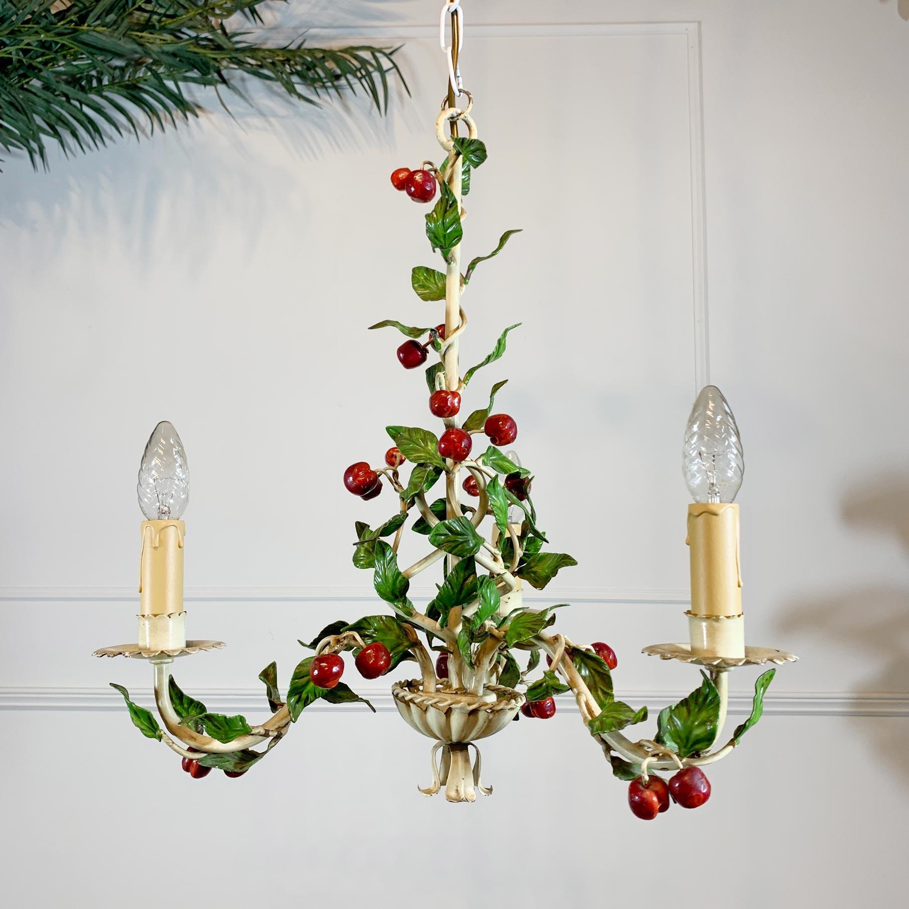 A charming 1950's Italian tole chandelier, the leaves and branches twist around the arms of the lampholders, resplendent in greens and red cherry fruit decoration, all original paint.

Each lamp holder takes a single e14 bulb.

To the base a