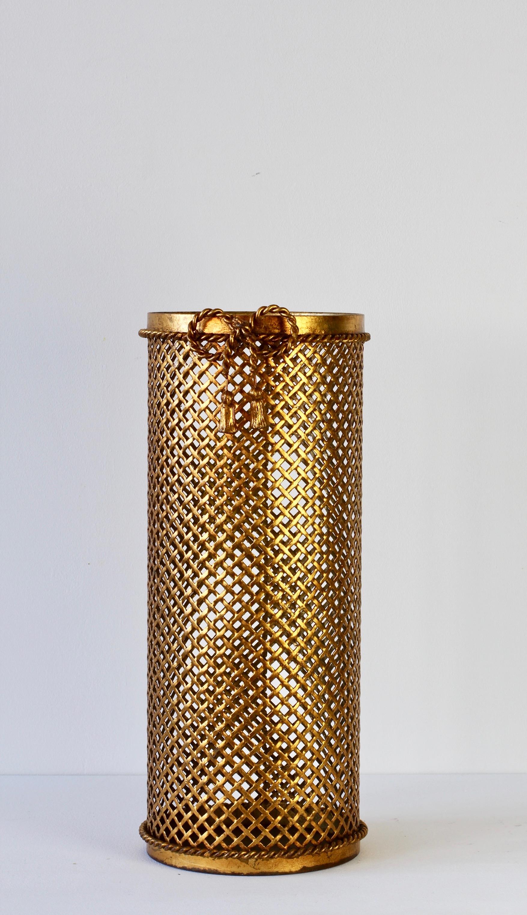 Stunning midcentury gold/gilt/gilded Hollywood Regency style umbrella stand or holder made in Italy, circa 1950. The perforated lattice patterned metalwork with elegant, thin bent rope and tassel details finish the piece perfectly.

This is a