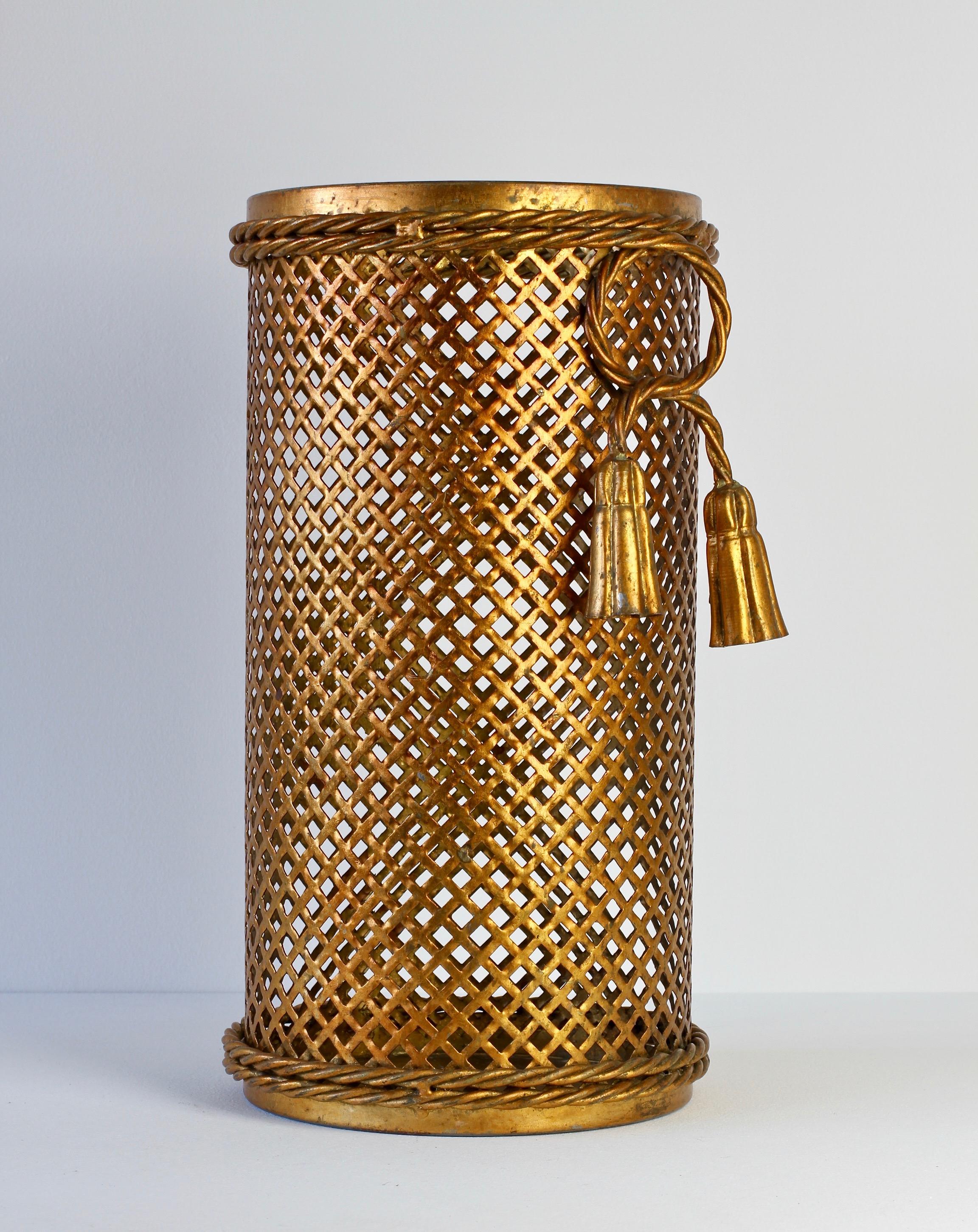 Midcentury gold, gilt, gilded Hollywood Regency style umbrella stand or holder made in Florence, Italy, circa 1950 by Li Puma Firenze. The perforated lattice patterned metalwork with bent rope and tassel details finishes the piece perfectly. 
