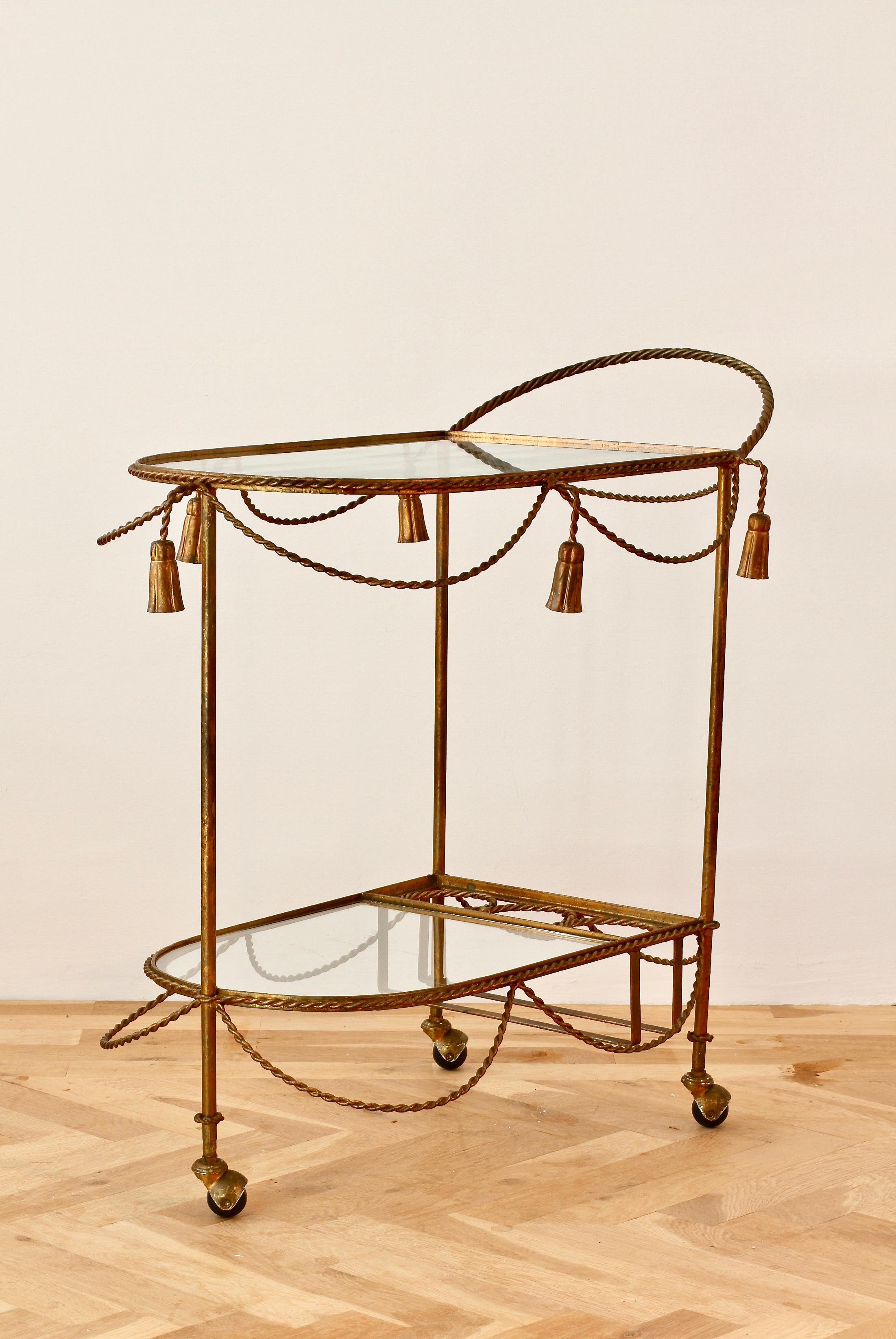 Vintage midcentury Italian Hollywood Regency bar cart / drinks trolley attributed to Li Puma Firenze, Italy circa 1950s. Made of gilt / gilded metal with beautiful twisted gold coloured rope and tassel details. Two glass shelves and integrated
