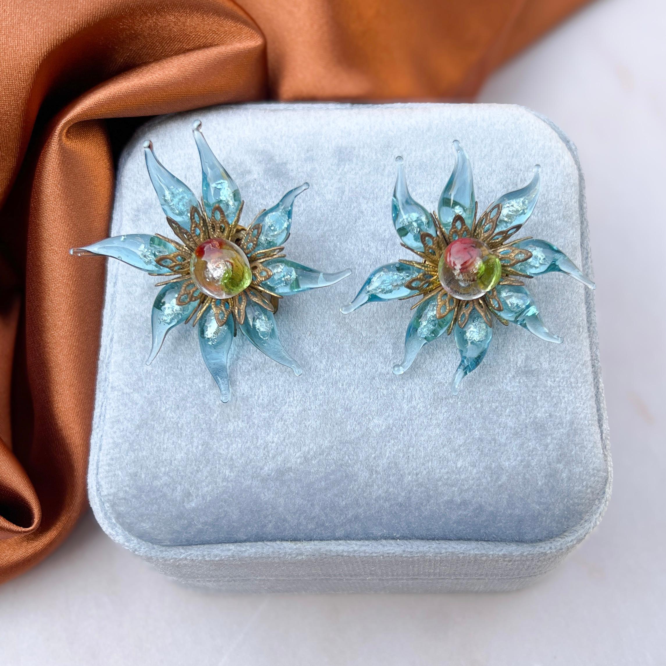 These clip on glass earrings are a lovely example of mid-century artisan craftsmanship.

Condition Report:
Excellent

The Details...
With a gilded metal base, these earrings feature flower motifs created from lamp work glass. The glass is enhanced