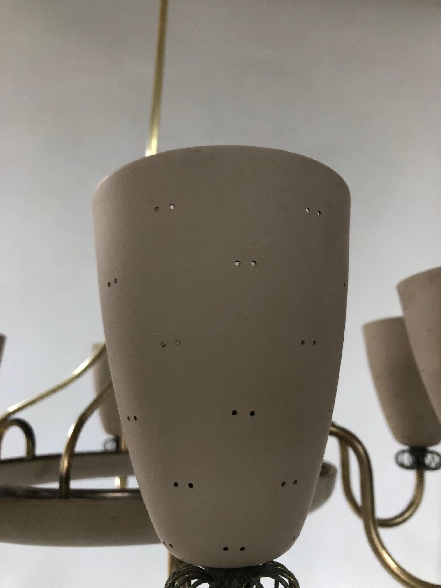 Mid-Century Modern enamel and brass chandelier by Paavo Tynell, The light fixture has a total of eight matte painted metal cones. Each cone has small holes where lighting will illuminate. 
Measures: 30 height (top to bottom) x 26 diameter. Each