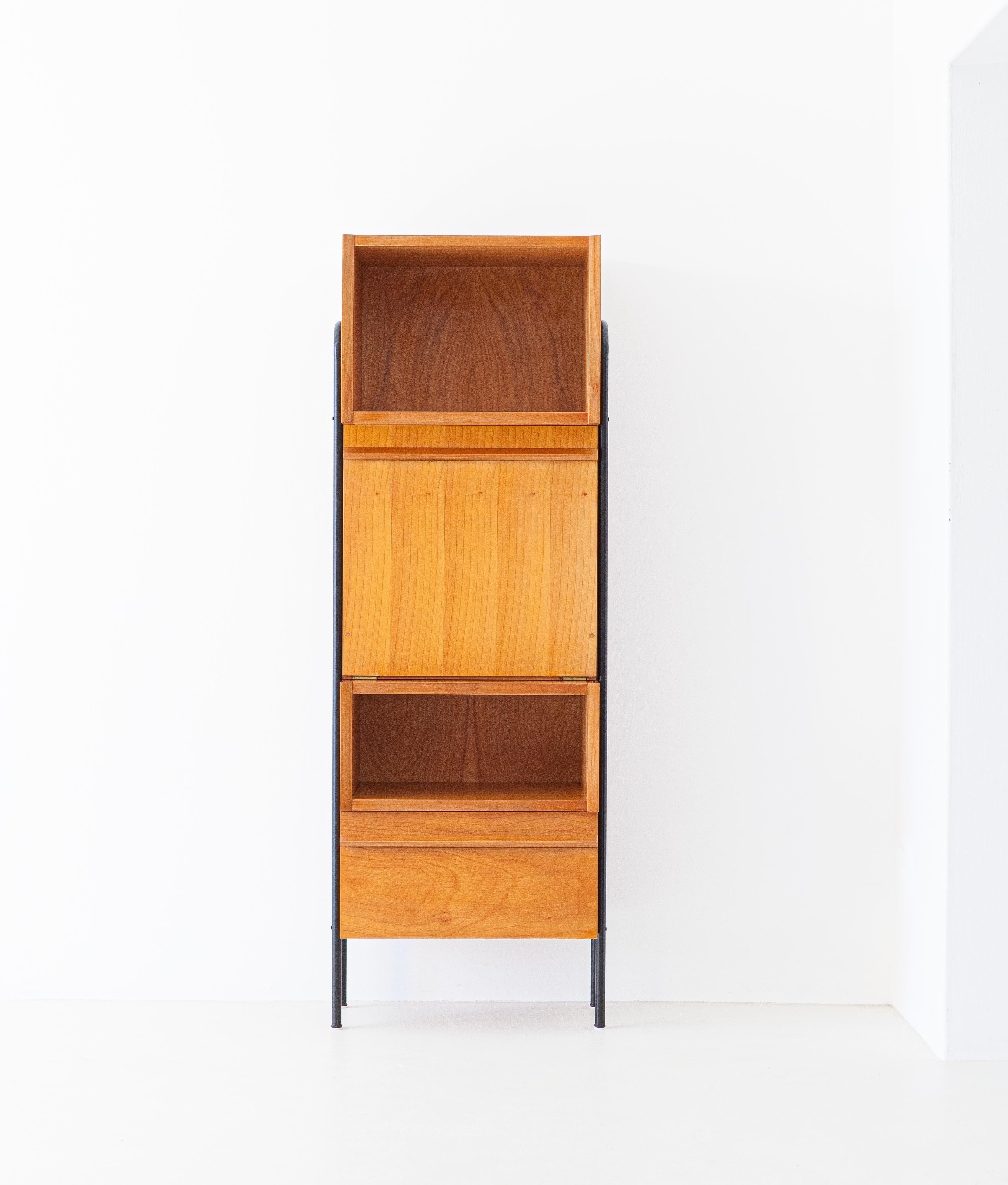 A modern multifunctional cabinet, manufactured in Italy during the 1950s
Veneered in light wood, milled wooden handles and black enameled iron legs.

This piece of furniture has two open containers, a very roomy flap door that can also be used as