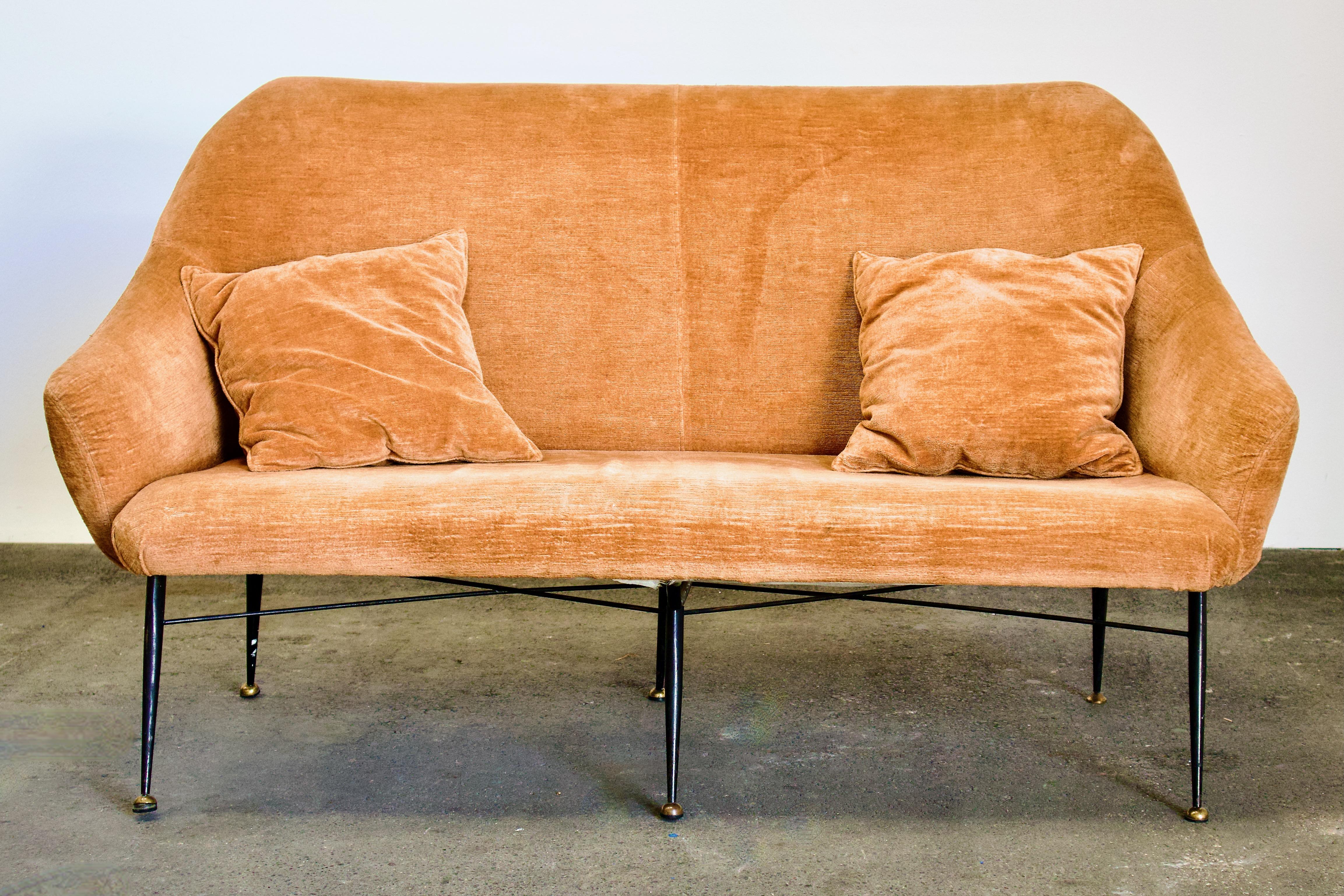 Chic 1950s upholstered Italian Loveseat, Gio Ponti attributed. The gorgeous curved / crescent / hugging shape of this loveseat is magnified by the perch of the slim, tapered and angled metal legs with hemispherical brass feet. Upholstery is velvet