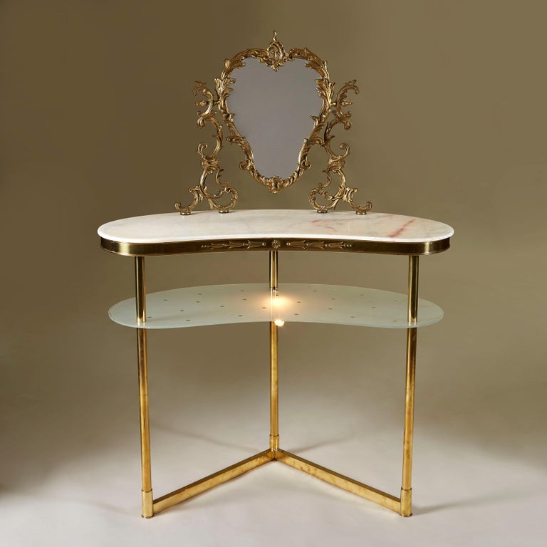 Two-tiered 1950s dressing-table in brass with honey coloured marble top. The glamorously ornate brass mirror is secured into the curved marble top. Frosted lower shelf is etched with a polka dots and sits over a small fitted light for an extra touch