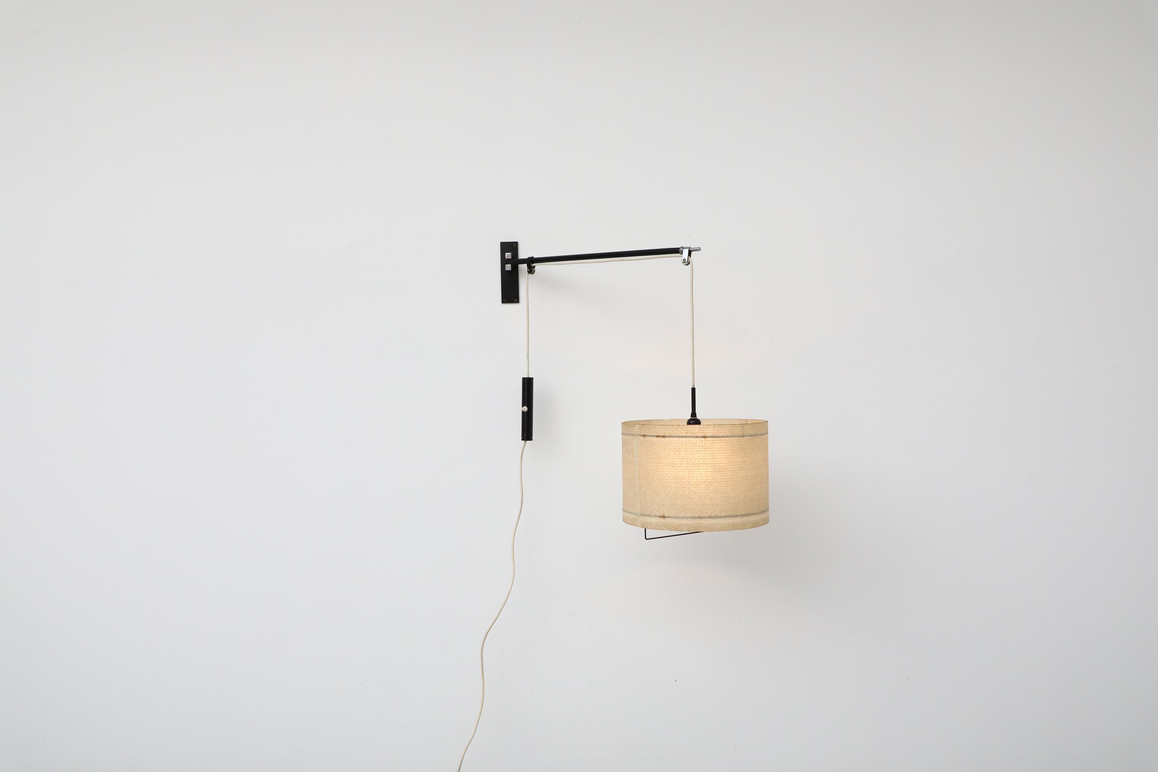 Hübsche italienische Wandlampe aus der Jahrhundertmitte. Diese Wandleuchte im industriellen Stil hat einen schwarz emaillierten Metallrahmen mit einem ausziehbaren Trommelschirm, der durch einen Lichtschalter mit Gegengewicht ausgeglichen wird! Eine