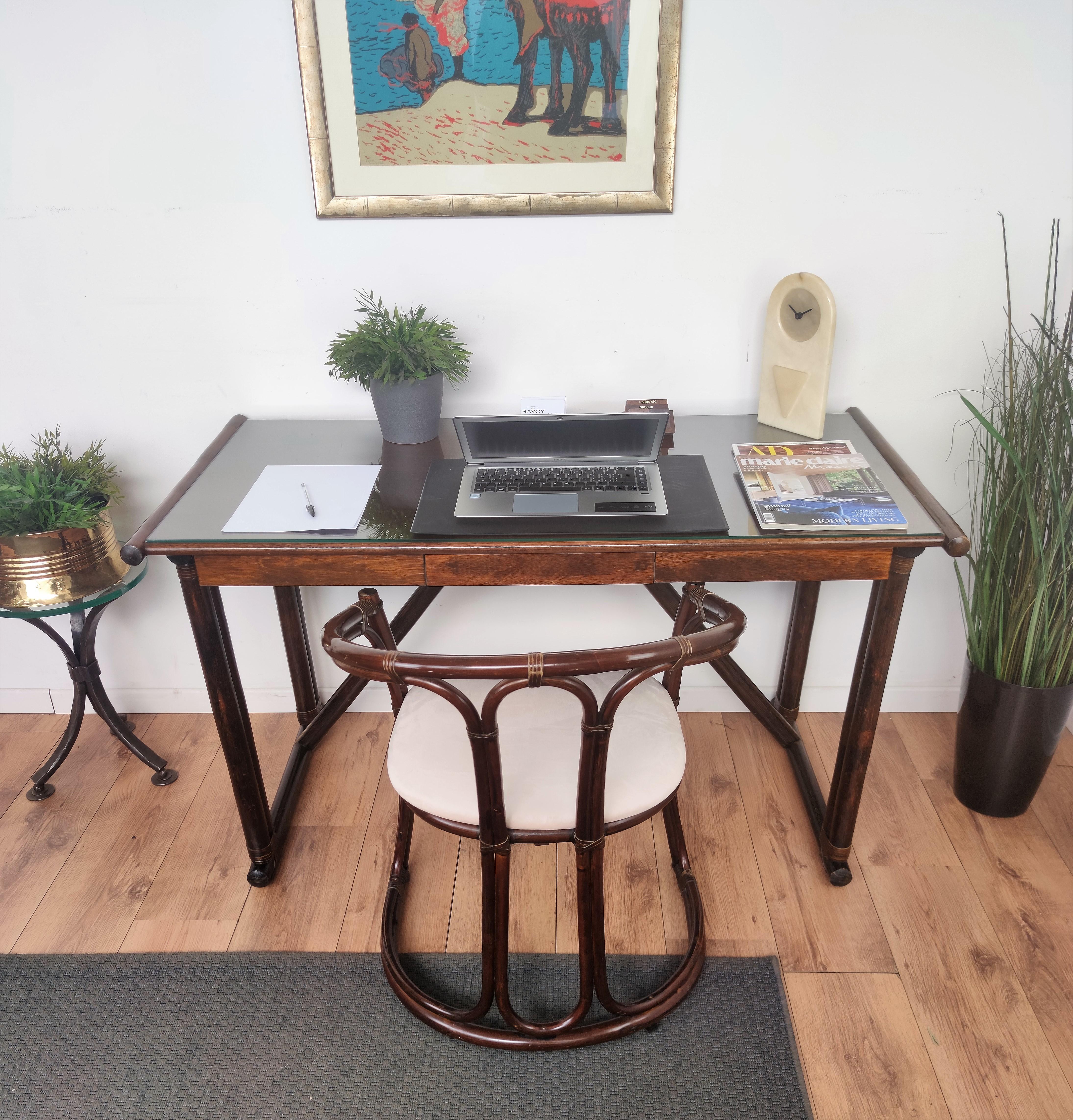 Beautiful mid-century Regency Italian writing table or desk with its paired newly upholstered chair both in greatly shaped and worked wood inspired to the typical bamboo organic bohemian style. 

The desk features a glass top, three drawers and