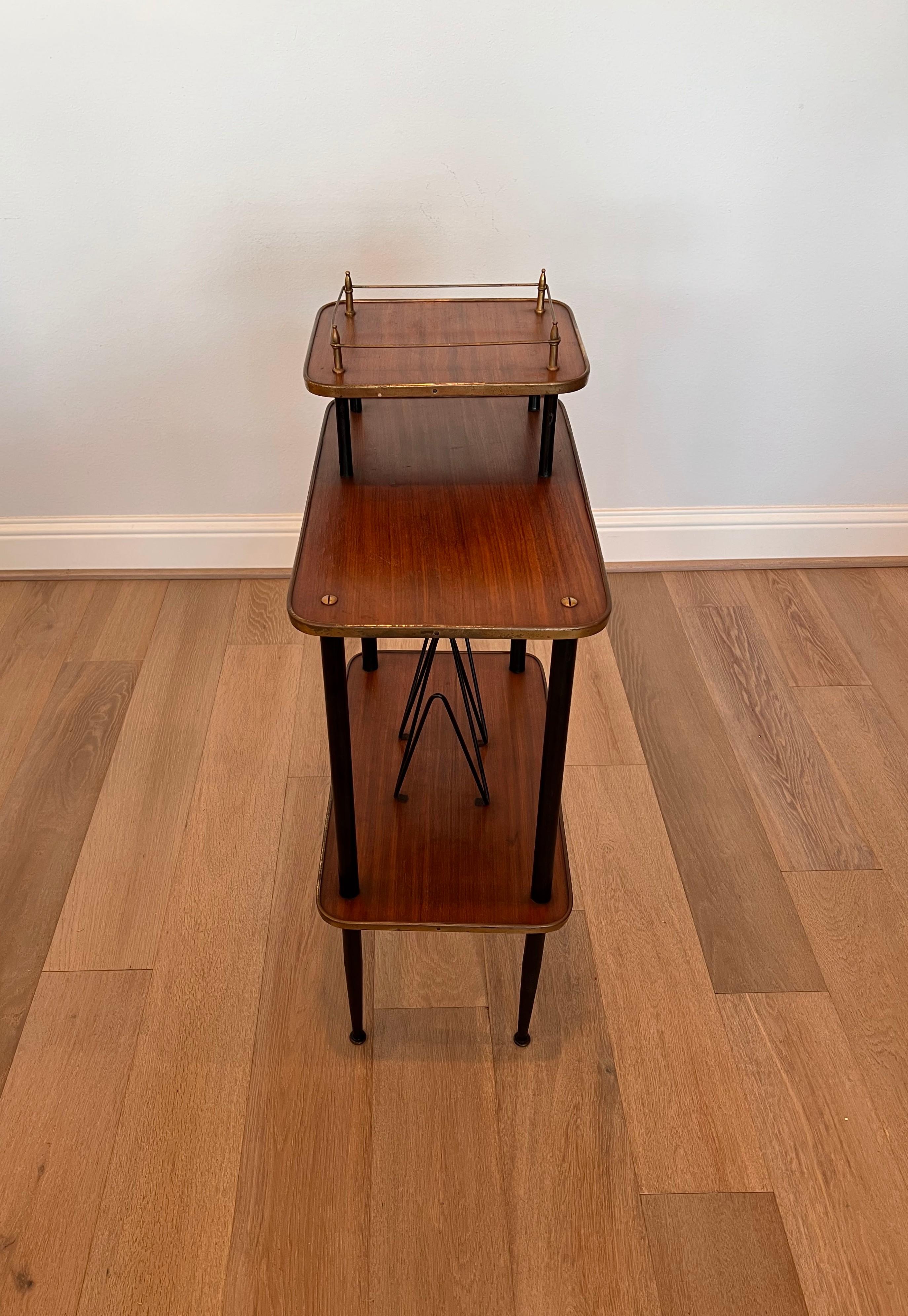 A vintage, circa 1950s, midcentury Italian modern tiered étagère side table. 

Born in Italy in the Mid-20th Century, crafted of teakwood, patinated brass and lacquered black metal, featuring an open three tier design, with square top tier having