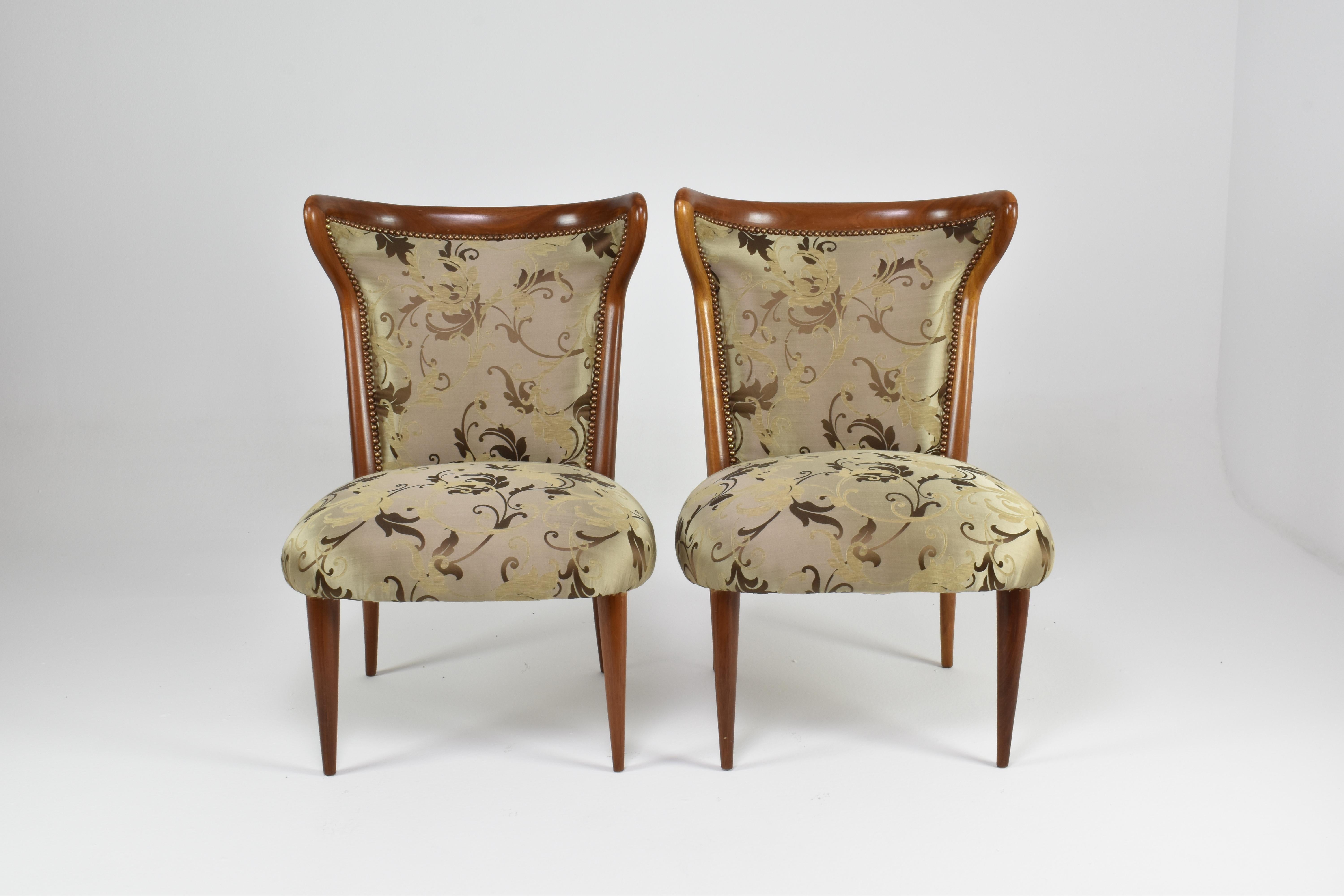A pair of mid-century Italian chairs distinguished by their sculptural silhouette and exquisite restoration. The exposed wooden frame curves inward at the top, forming a distinctive winged backrest with a subtle cinched profile — a sophisticated