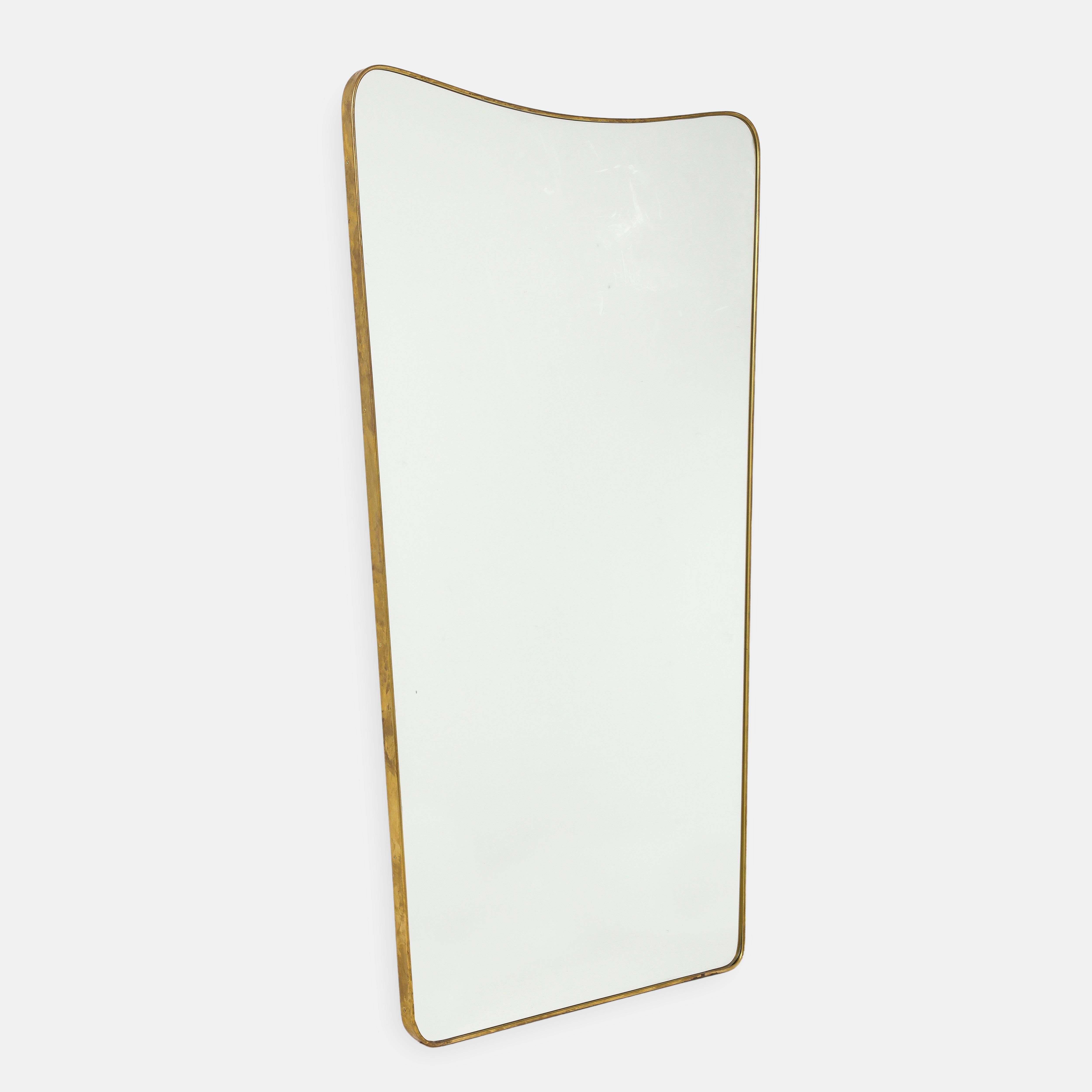 1950s Italian modernist grand scale wall mirror consisting of shaped brass frame with gently arched and rounded top which slightly tapers towards the bottom This chic and rare mirror is large and striking in size especially its width which is larger