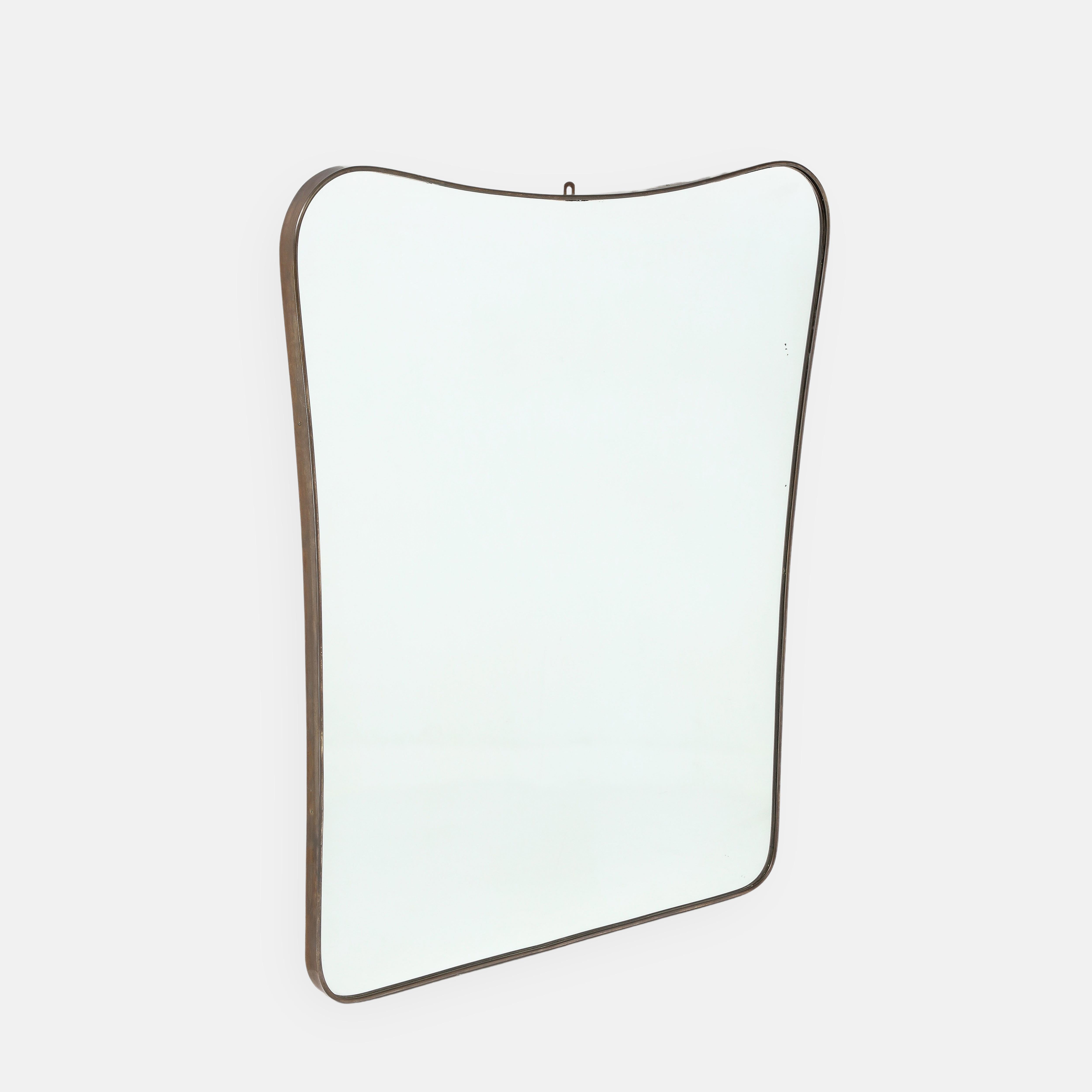 1950s Italian modernist large wall mirror consisting of shaped brass frame with gently arched top and rounded corners which tapers towards the bottom.  It's unusually wide and large in scale making a bold statement in any interior whether classic or