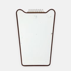 Espejo biselado modernista italiano de mediados de siglo, nogal, latón y volutas, años 50