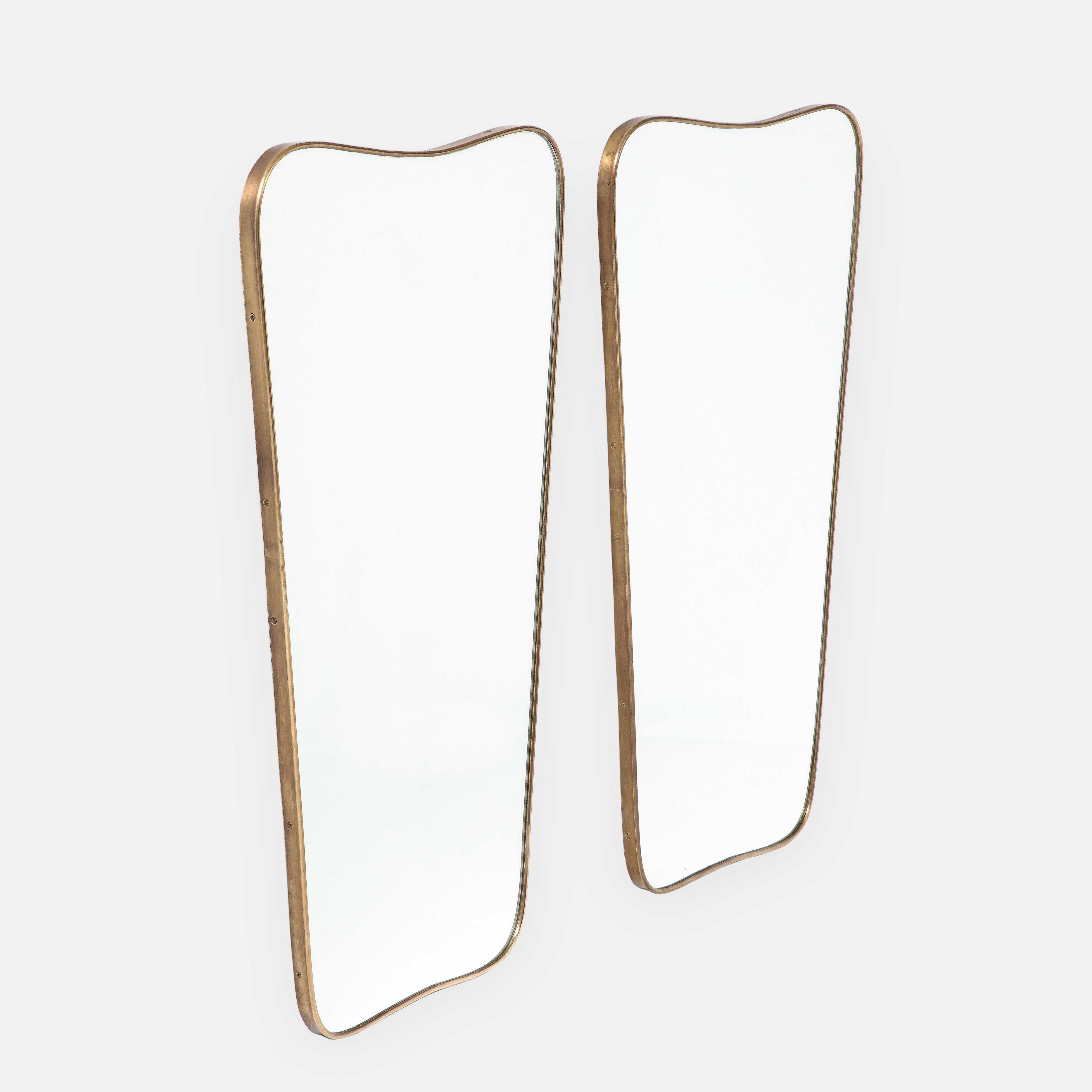 1950s Italian modernist pair of large wall mirrors consisting of shaped brass frames with gently arched tops and rounded corners which taper towards the slightly arched bottoms. These chic pair of mirrors are truly an iconic Italian midcentury brass