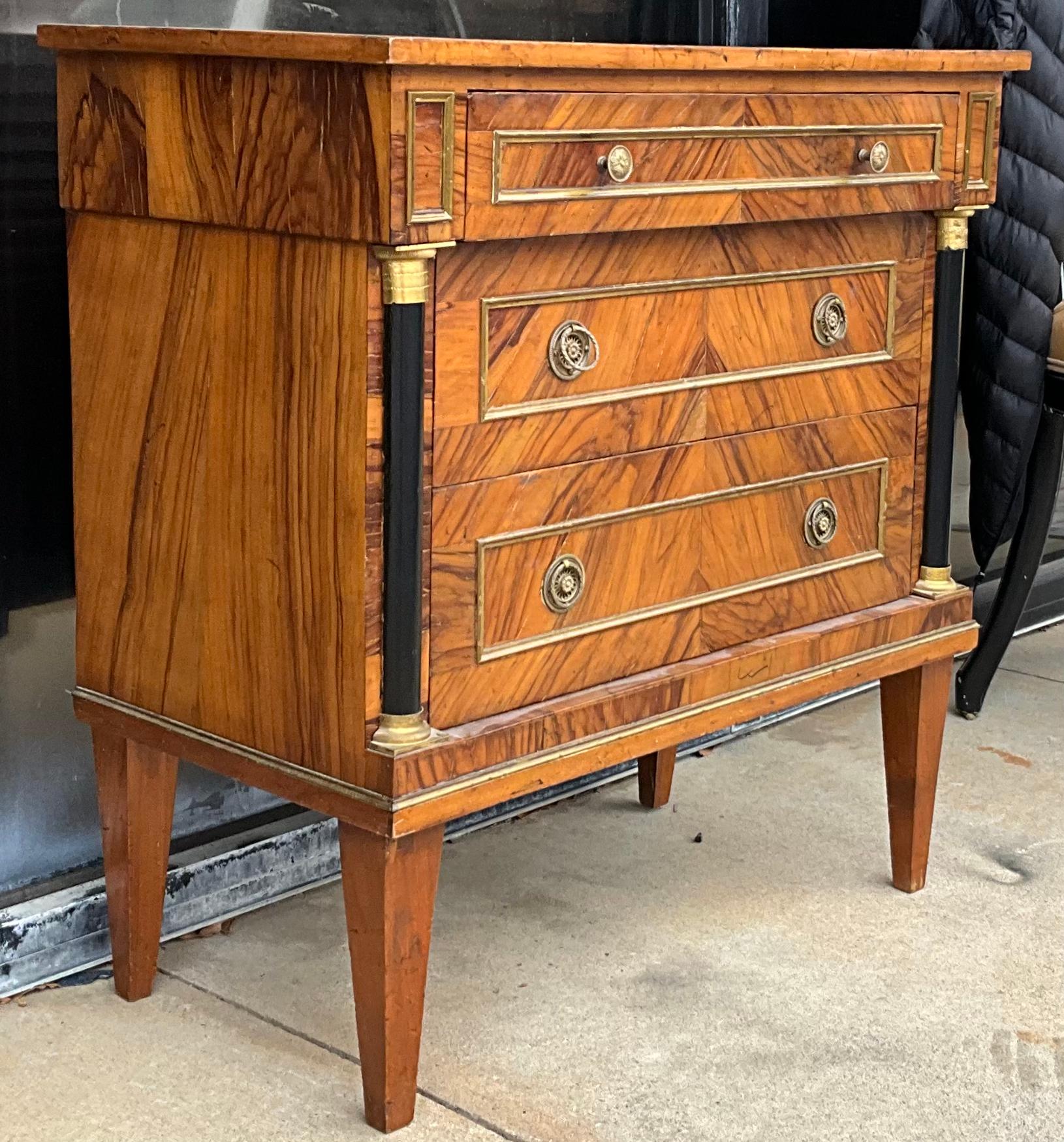This is a 1950s Italian neo-classical style walnut chest. It has ebonized and gilt columns and the original brass hardware. The drawers are lined in paper, and the label is on the back. Such a handsome piece!