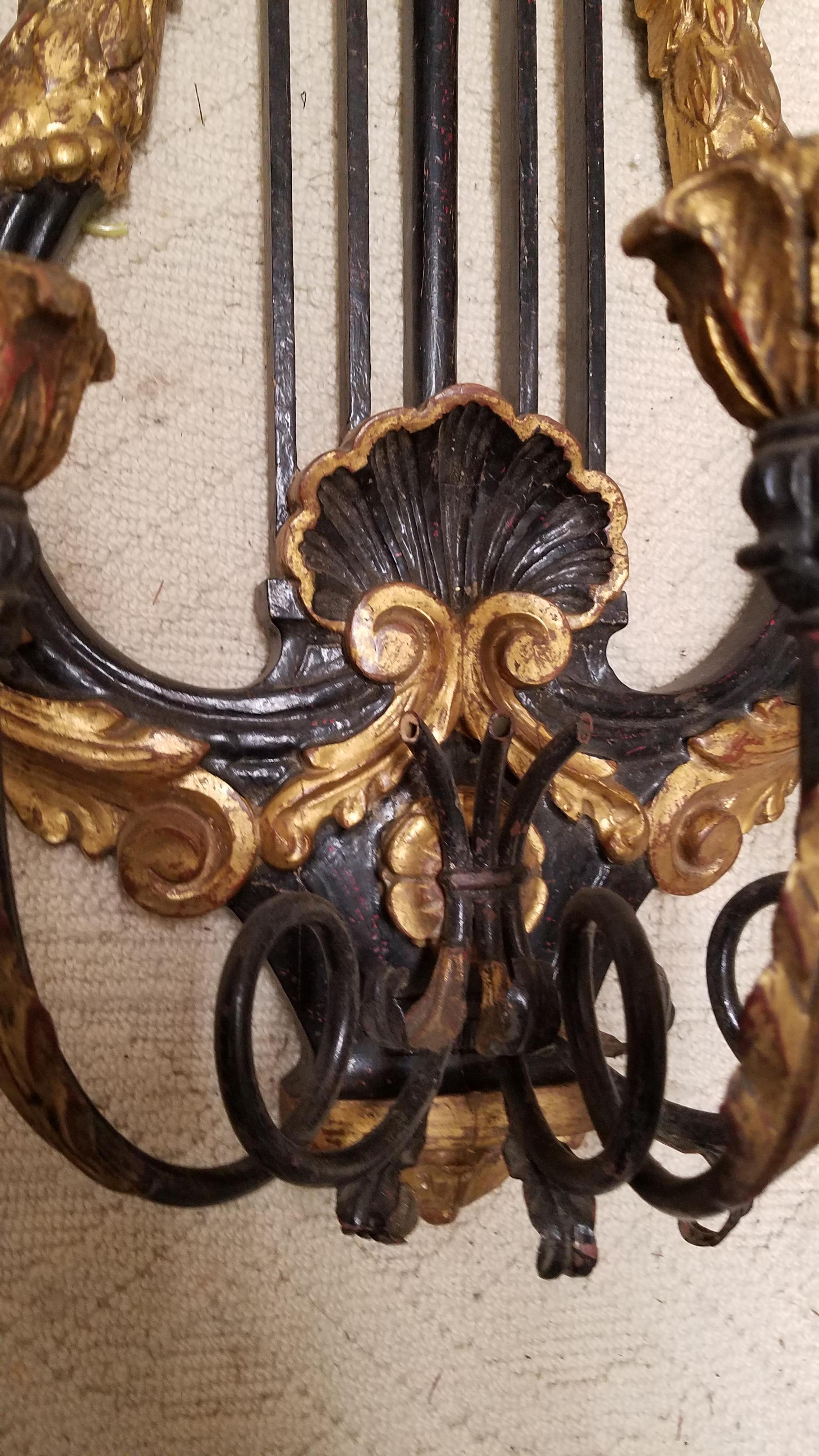 The black and gold hand carved wood sconce with lyre back plate in gold and black. The gilt and black shell carvings with gilt griffons with three arms for candles, this sconce has not been electrified.
