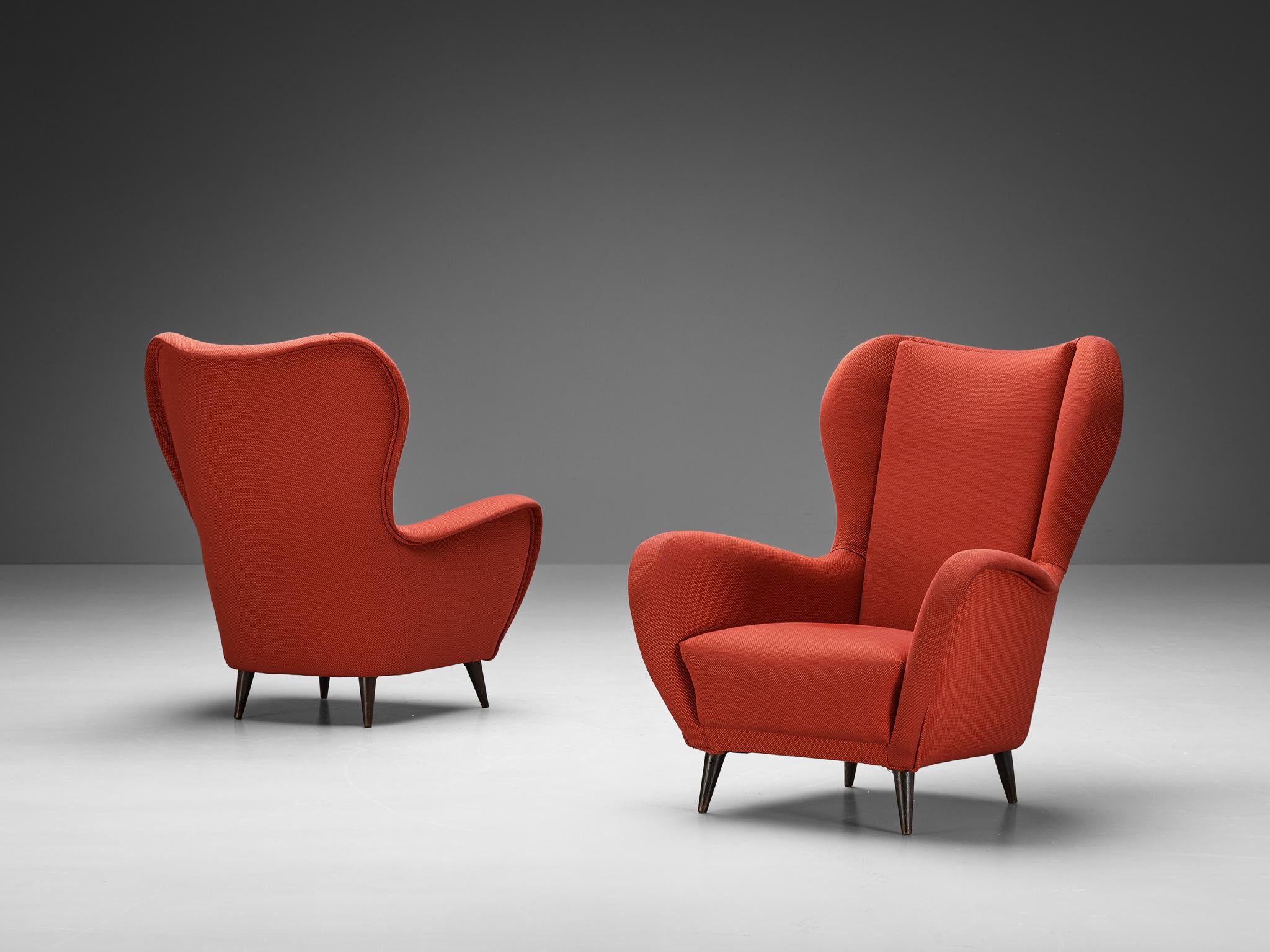 Pair of easy chairs, fabric, wood, Italy, 1950s.

These lounge chairs are both voluptuous and grand as they are comfortable. The chairs embody a semi-high wingback composed of curvaceous lines. The design fits perfectly into the Italian ethos of the