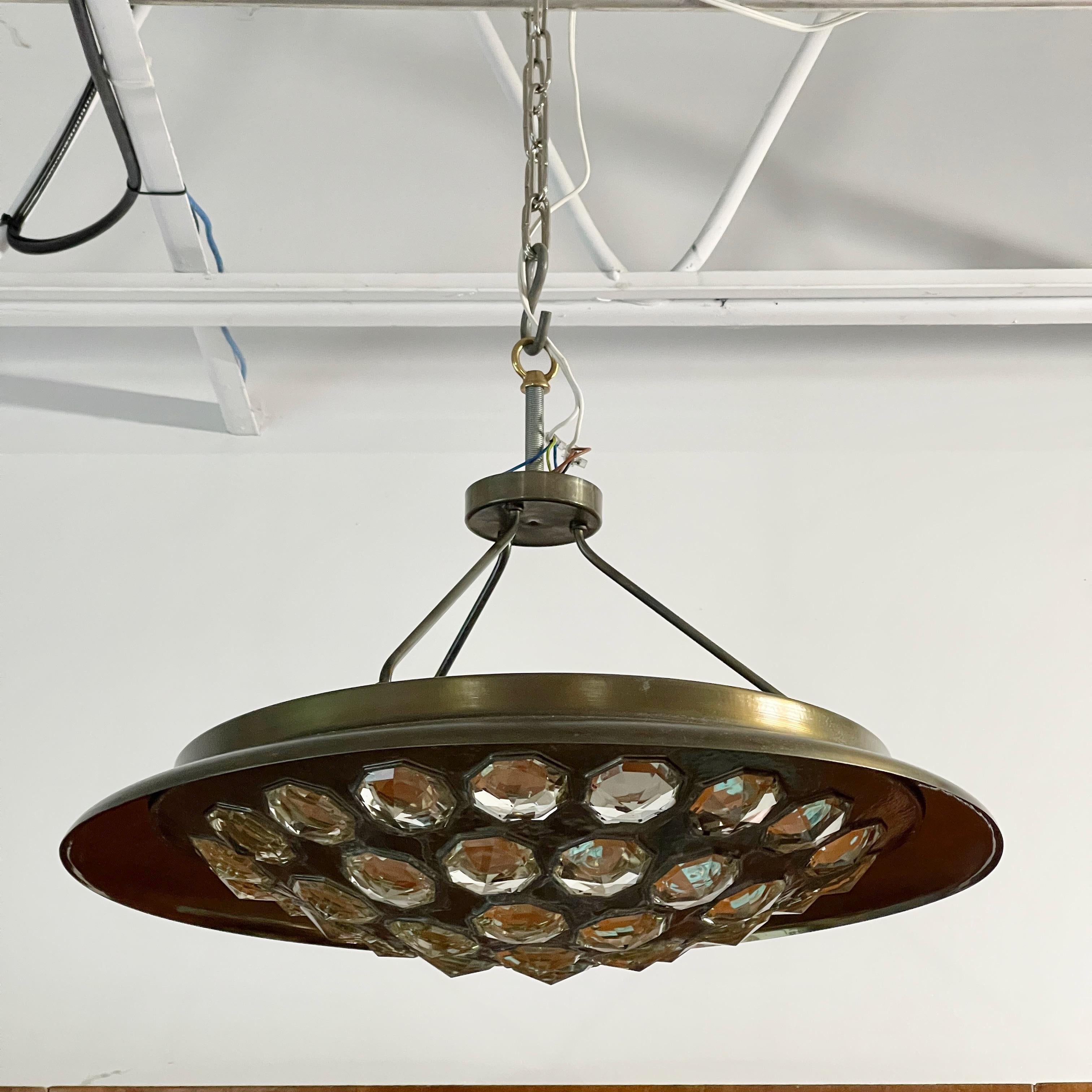 Unique UFO-form pendant light in finely hammered and patinated nickel-plated brass and set with several dozen octagonal cut crystal gems and illuminated from within by six standard size Edison screw cap lightbulbs designed by Edera Radici for SAGIM