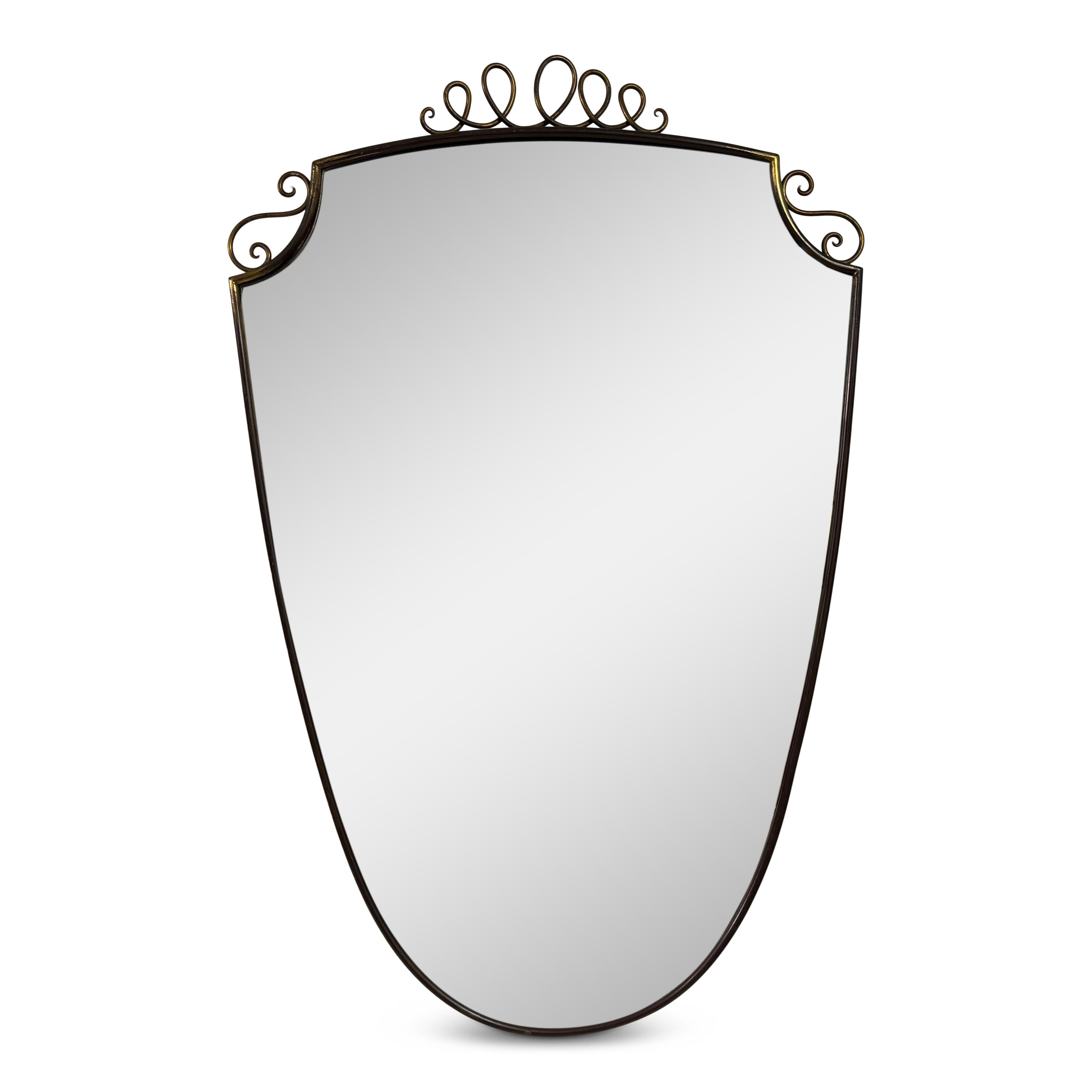 1950s Italian Patinated Brass Mirror with Scroll Detailing

A charming example of mid-century Italian design, this 1950s wall mirror is all about quiet glamour and graceful lines. The shield-shaped form is framed in slender brass, patinated with