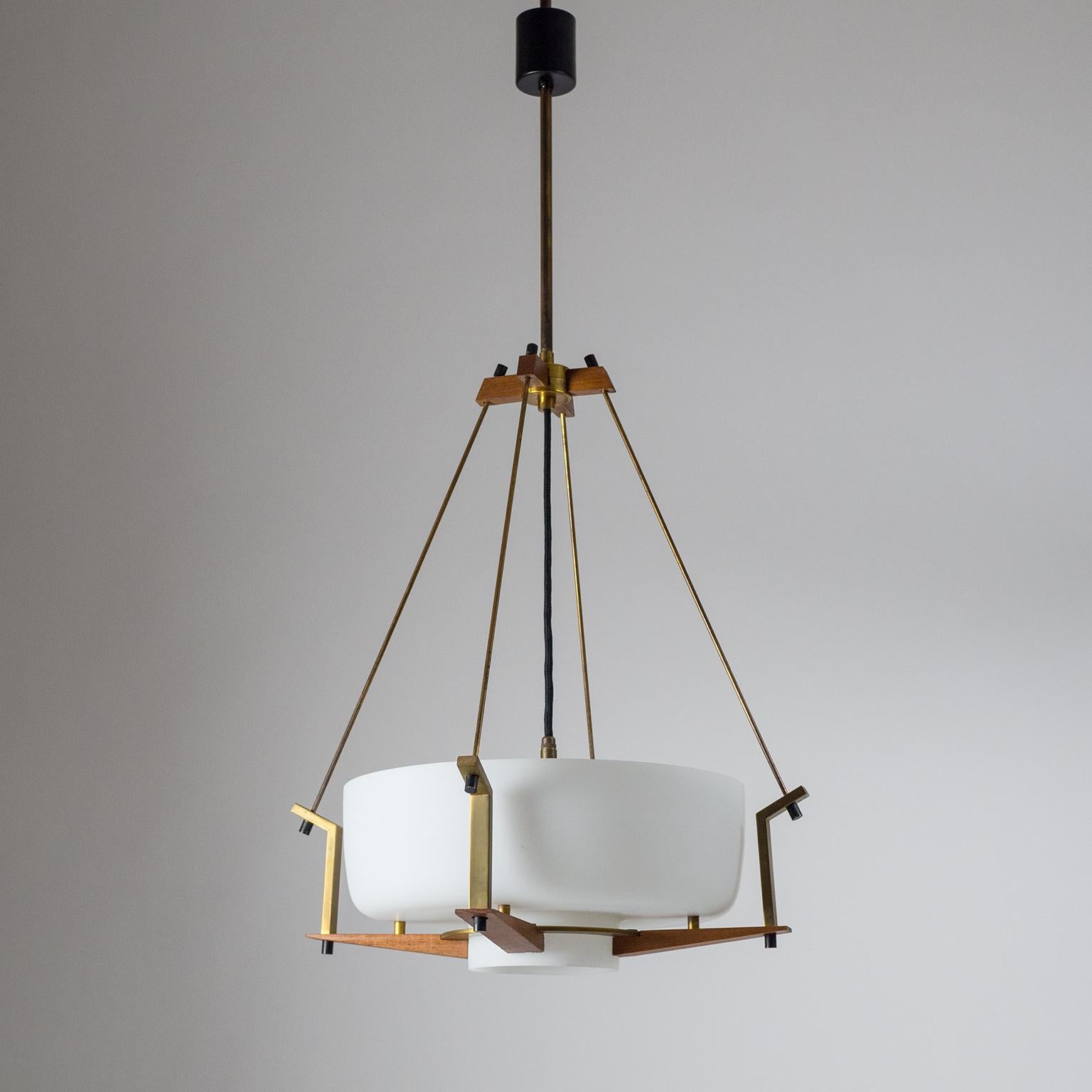 Architectural Italian pendant or chandelier from the 1950s. A large blown satin glass diffuser is placed in an intricate suspension structure of brass and teak. The whole appearance has a very architectural quality by emphasizing the constructional