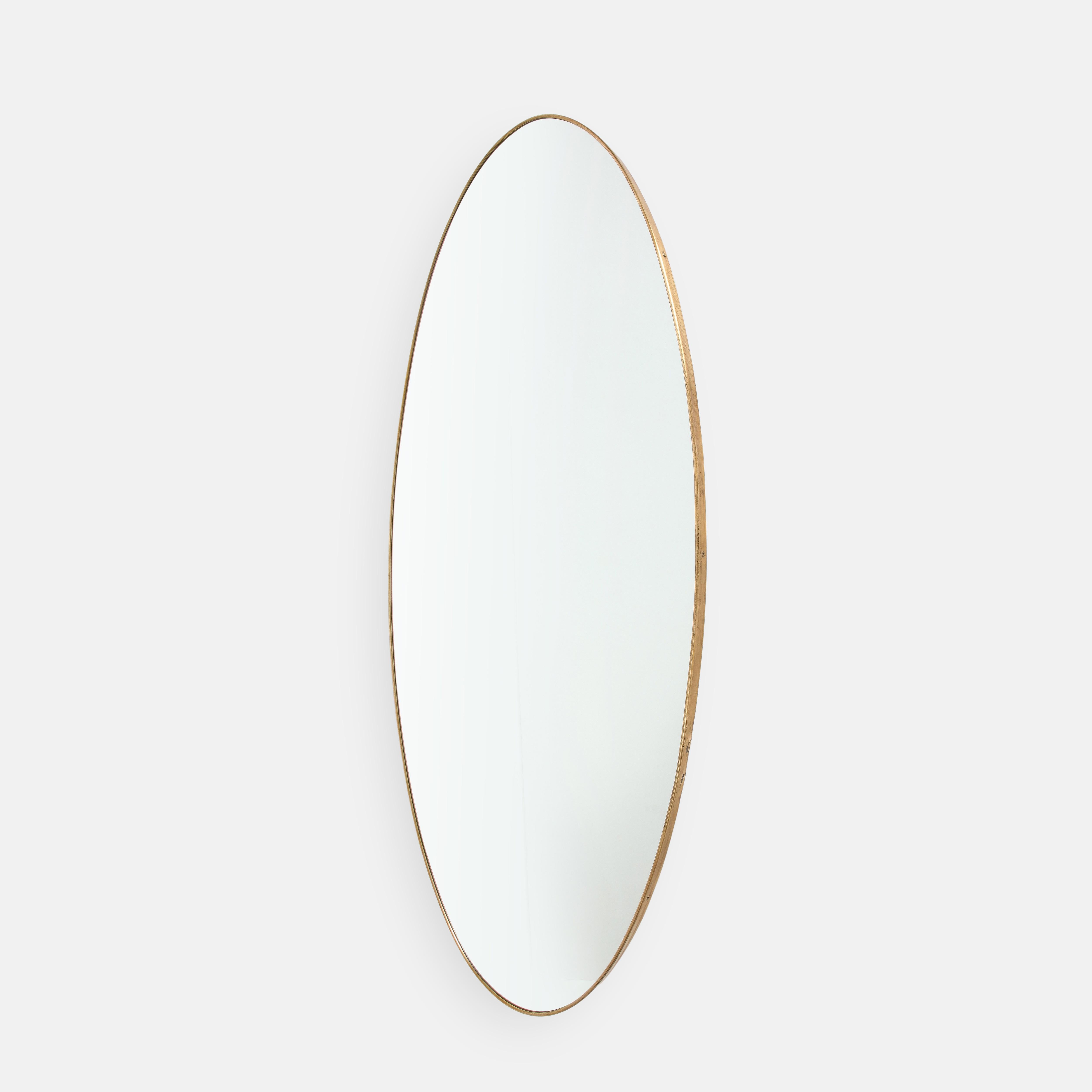 1950s Italian rare grand scale oval wall mirror. This elegant mirror is large and striking in size and has a beautiful rich patinated shaped brass frame and solid construction with wood backing. This monumental size brass mirror is very rare to find