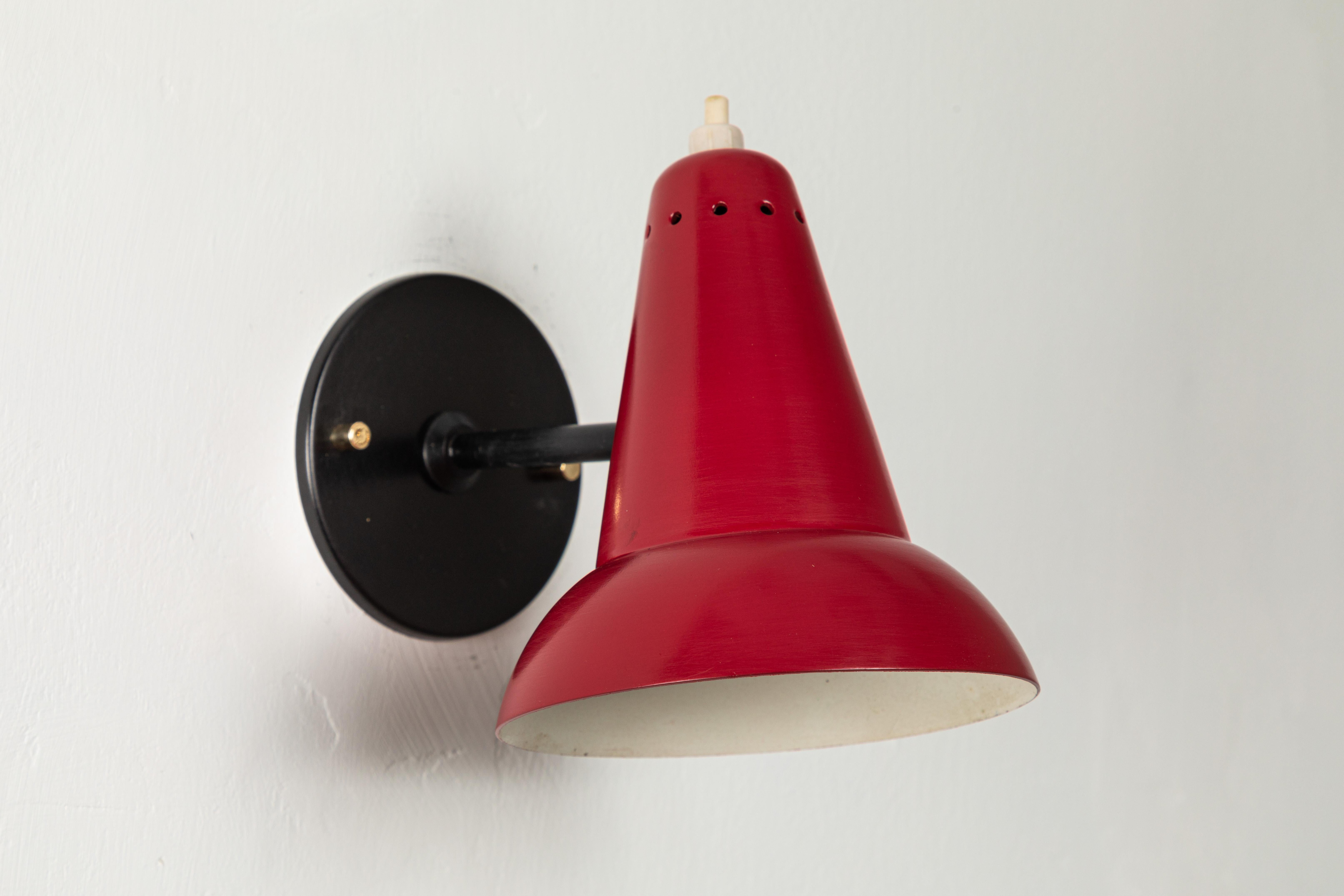 1950s Italian red articulating sconce attributed to Gino Sarfatti. Executed in brass and red painted aluminum. Sconce pivots up/down and left/right on a ball joint. Custom black backplate with brass hardware for hardwiring mounting over standard US