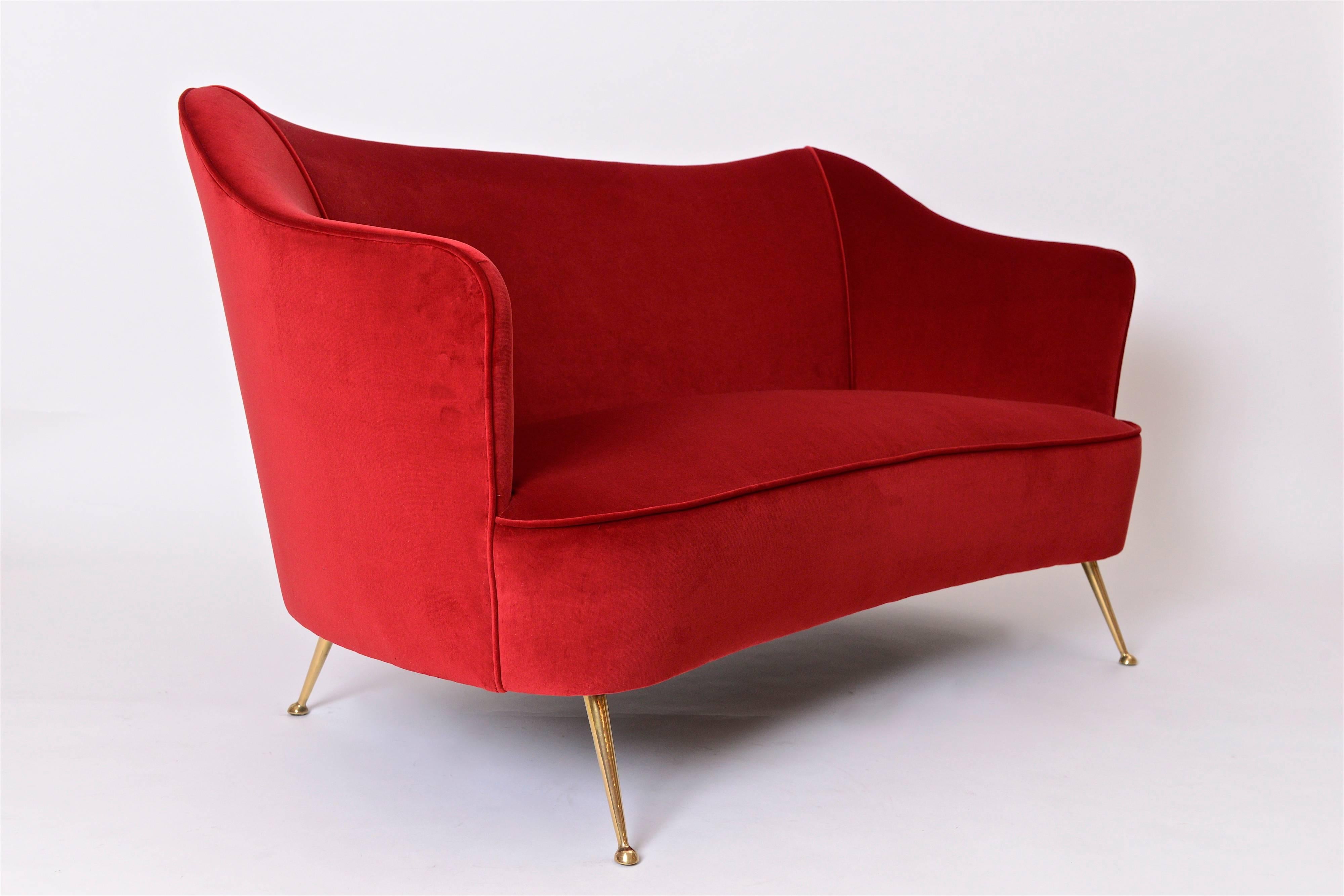 A very attractive three-piece lounge suite comprising of a two-seat settee and its two matching chairs. Newly upholstered in a chic, blood red velvet by Holland and Sherry, the suite rests on its elegantly splayed polished brass legs. The wonderful,