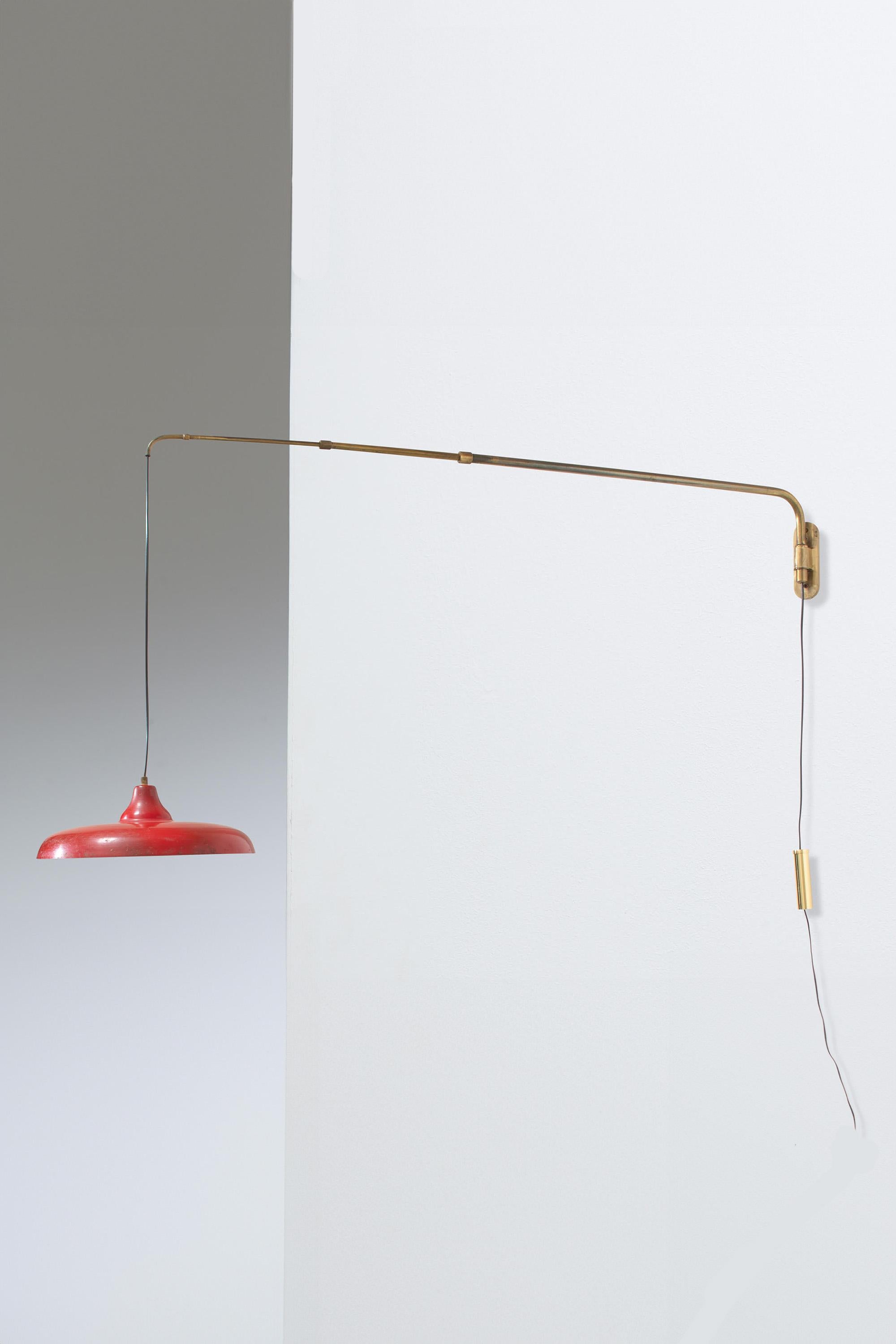 
Italienische Wandlampe aus Messing und Aluminium aus den 1950er Jahren mit rot lackiertem Metallschirm.

Der Messingschalter ist mit einem Gegengewicht versehen, um die Höhe des Schirms zu regulieren - wenn er nach unten gezogen wird, wird der