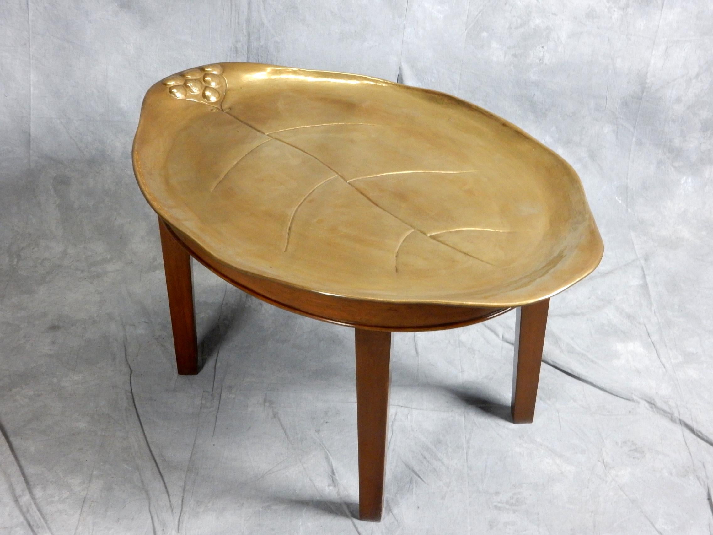 Exceptional quality artisan sculpted tray coffee table.
Hand hammered and crafted brass tray top in the shape of a leaf
with a custom made 4 leg wood base. 
Inset footed tray lifts off base with ease but is secure(will not slide) when in