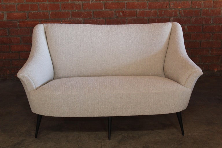 A vintage 1950s Italian settee on walnut legs. Completely restored and reupholstered in a wool blend nubby boucle. The legs have been refinished satin black.