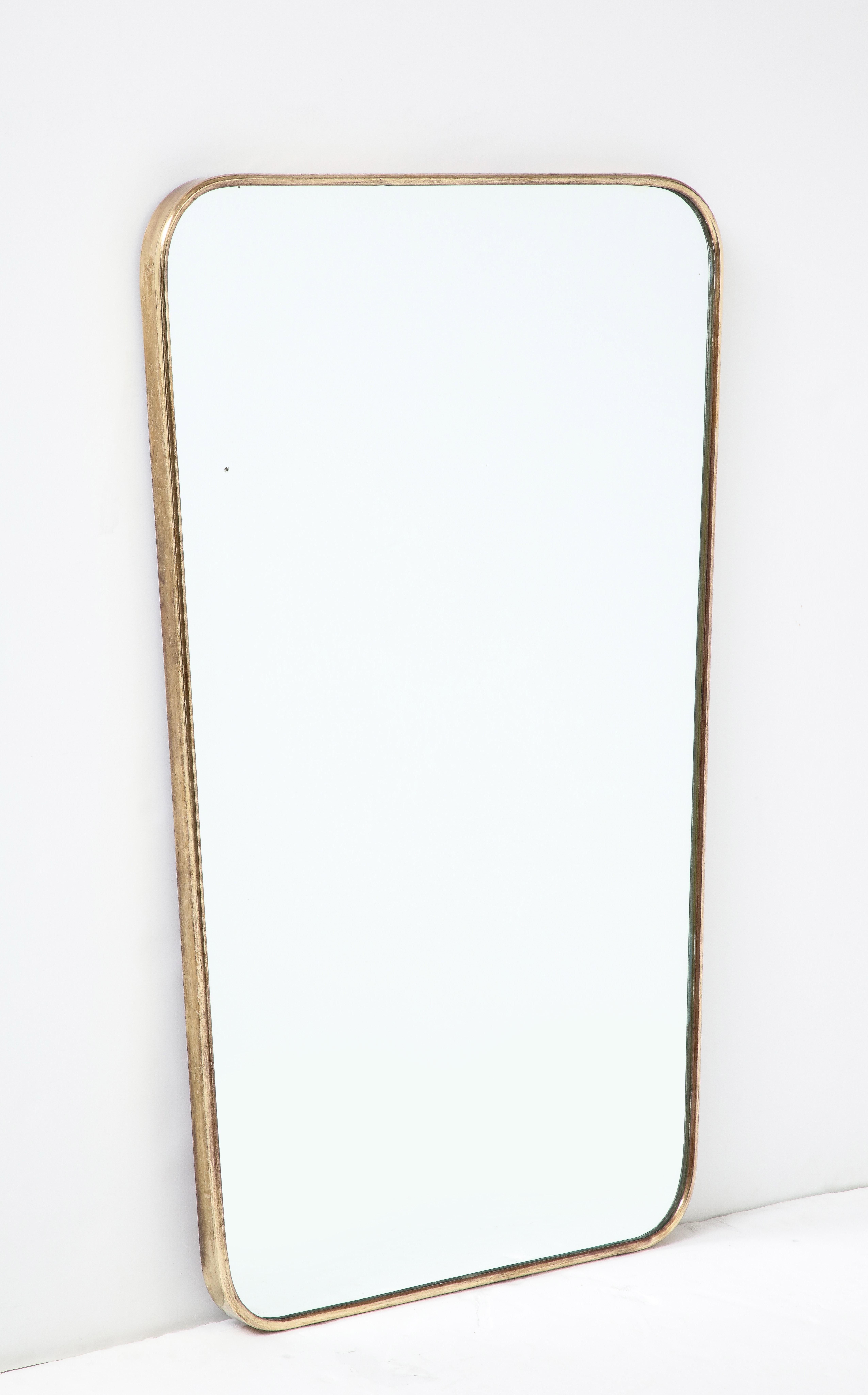 1950s Italian lovely shaped brass wall mirror with gently curved corners and tapering towards the bottom. The brass frame has a beautiful aged patina and original mirrored glass with wood backing.
