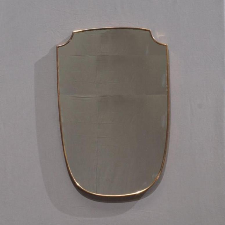 The 1950s Italian Shield Shape Wall Mirror is a striking embodiment of mid-century elegance. This unique mirror features a classic shield-shaped design, expertly framed in brass, showcasing the impeccable craftsmanship typical of 1950s Italian