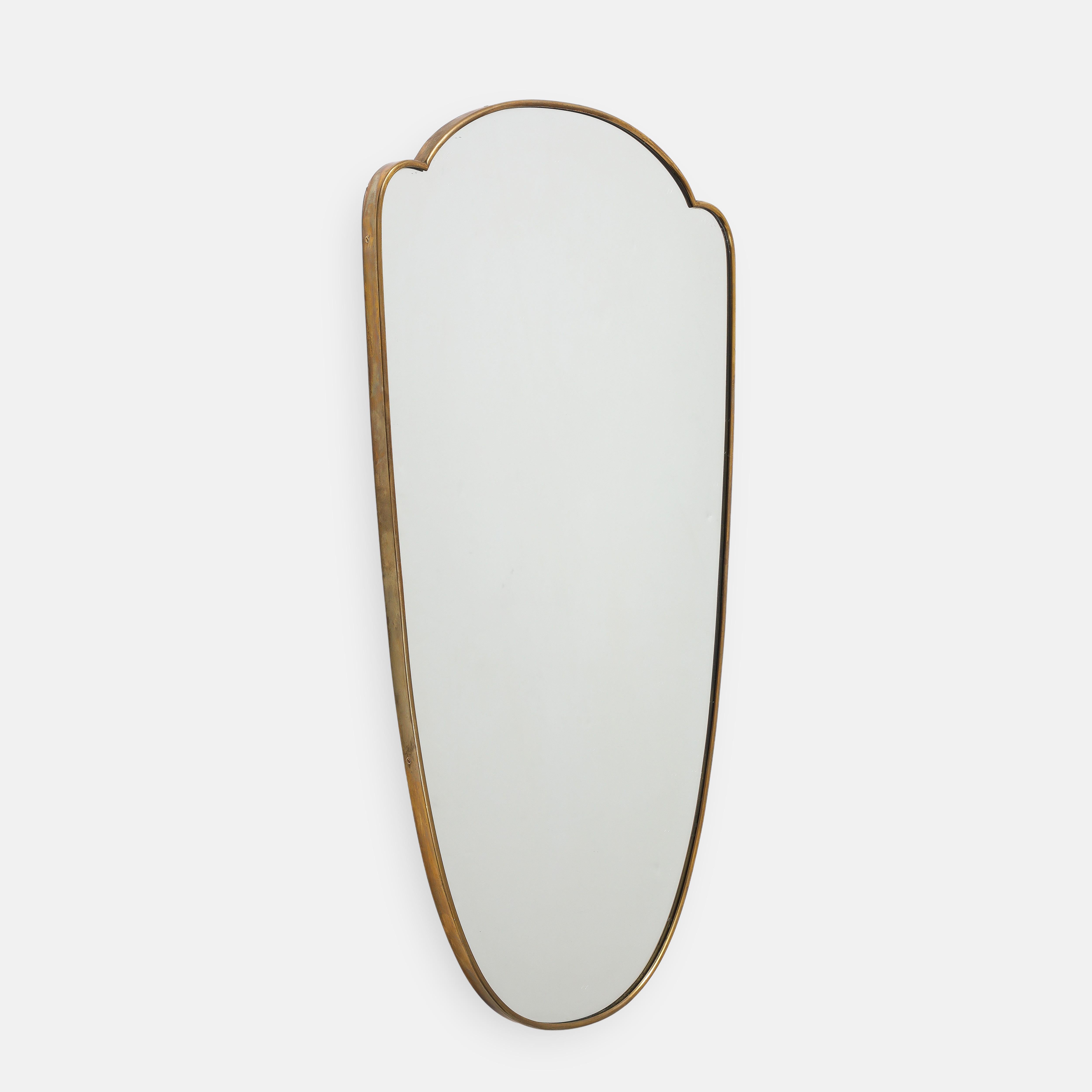 1950s Italian elegant shield shaped brass wall mirror. This original midcentury period mirror has a lovely elongated and curved form and a beautiful rich patina to the brass with wood backing.